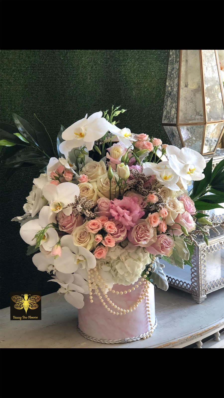 Pink and white floral arrangement in a round pink box with pearl trim