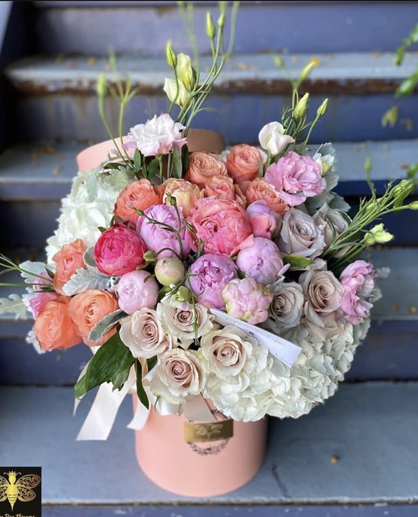 Pink and peach rose bouquet with white hydrangeas in a pink hatbox