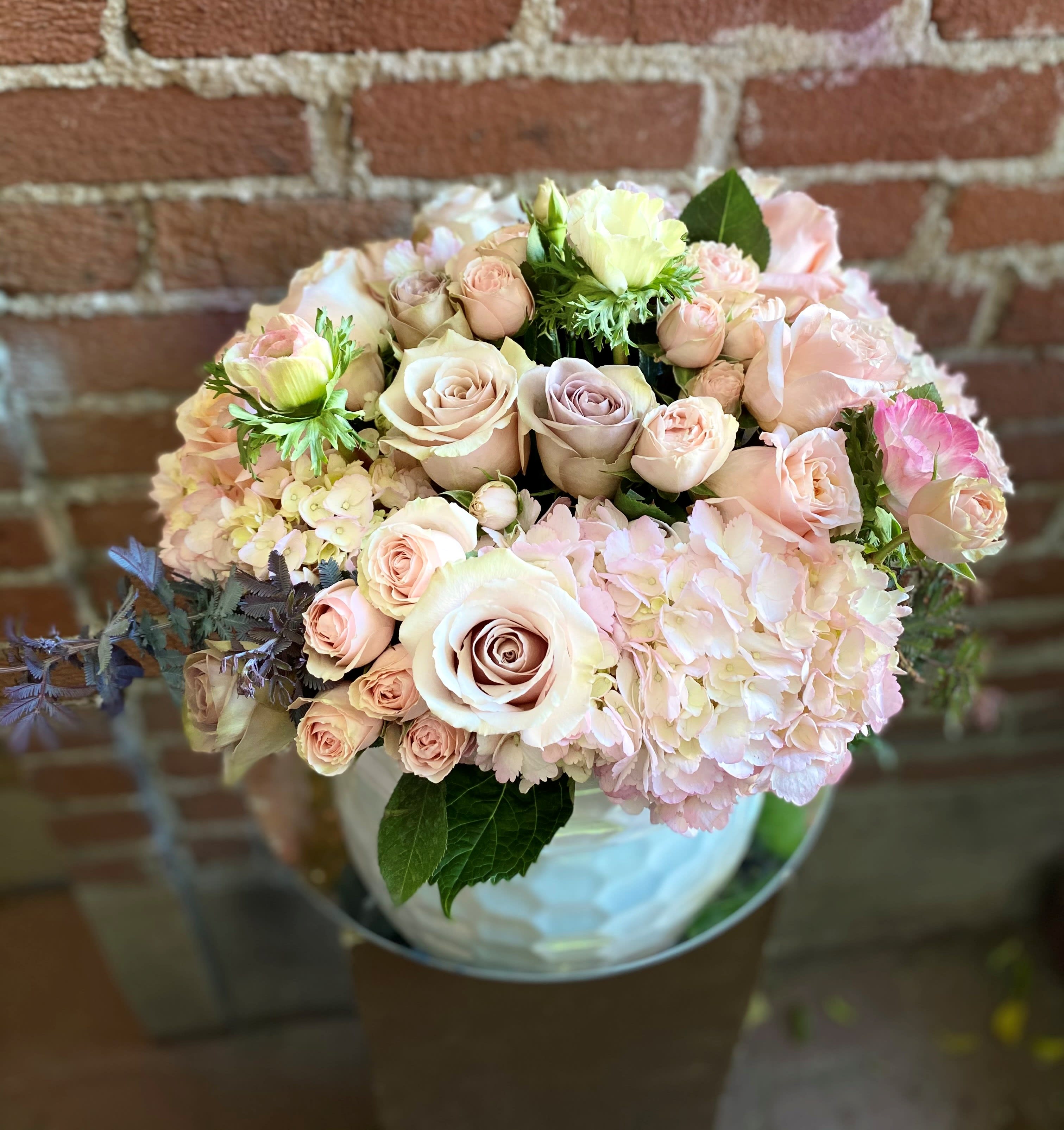 Bouquet of pale pink and cream roses with hydrangeas in a glass vase