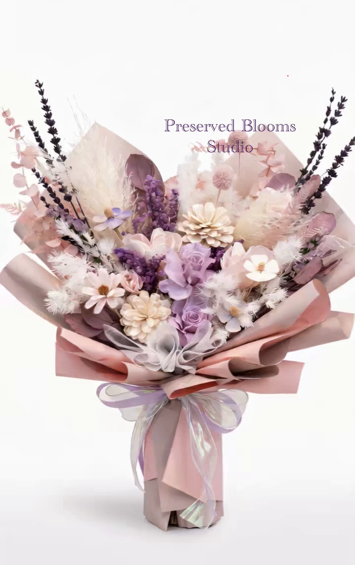 Devoted Love - This bouquet of immortal flowers from Preserved Blooms Studio, with its gentle tone and rich sense of hierarchy, is very suitable as a Mother's Day gift to express love and gratitude. The following are the main features of this bouquet:  Color matching: soft and eternal soft pink and lilac purple: the main color is warm pink and elegant purple, symbolizing the mother's love and gentleness. Beige embellishment: interspersed with white flowers and fluffy materials, adding a sense of purity and brightness to the whole. 