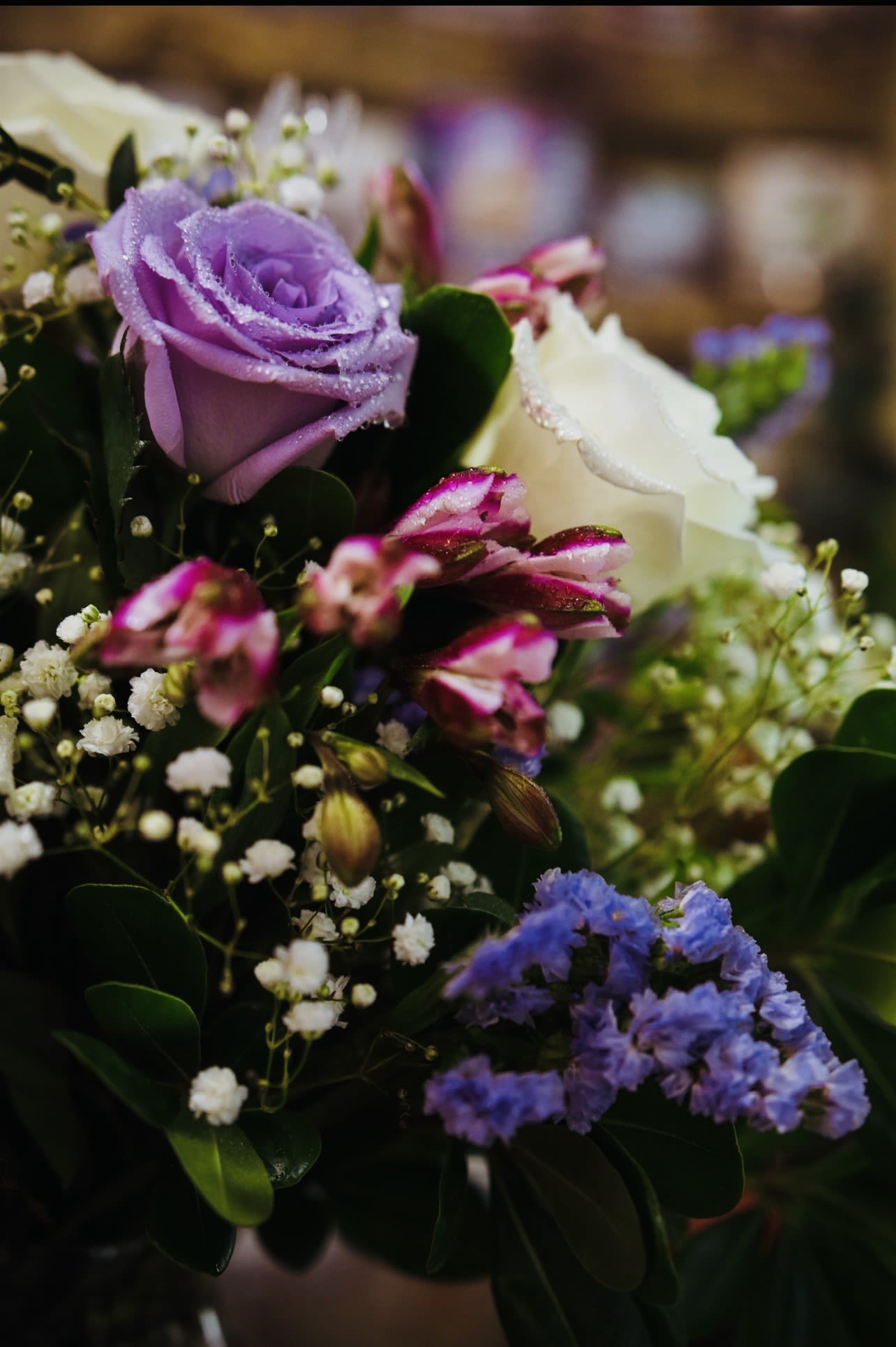 Bouquet of purple and white roses with small filler flowers