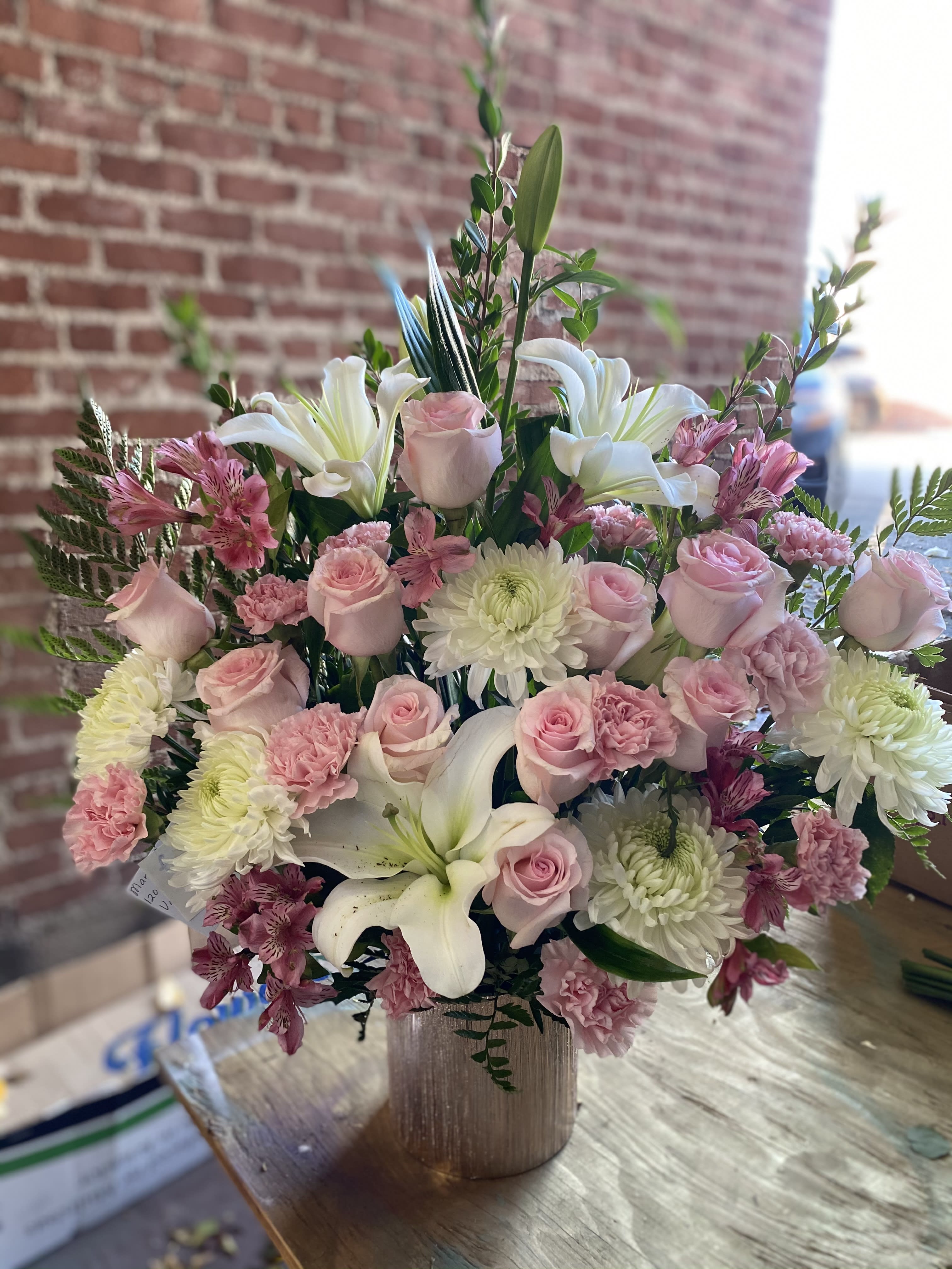 Pink roses and white lilies arranged in a vase with pink and white blooms