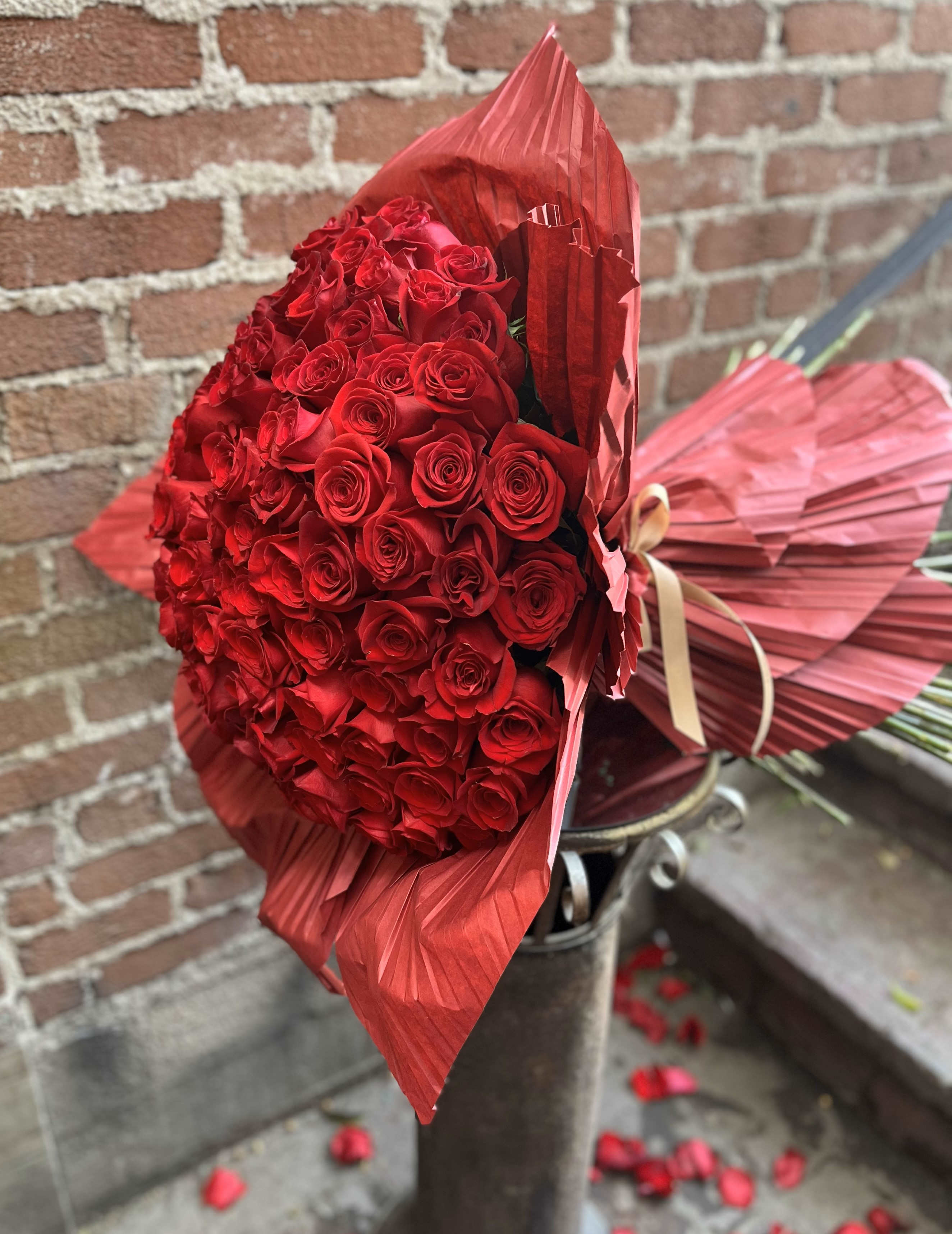 Large bouquet of red roses wrapped in red paper with a ribbon