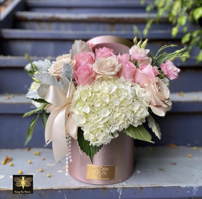 Pink and cream roses with white hydrangea in a pink hatbox