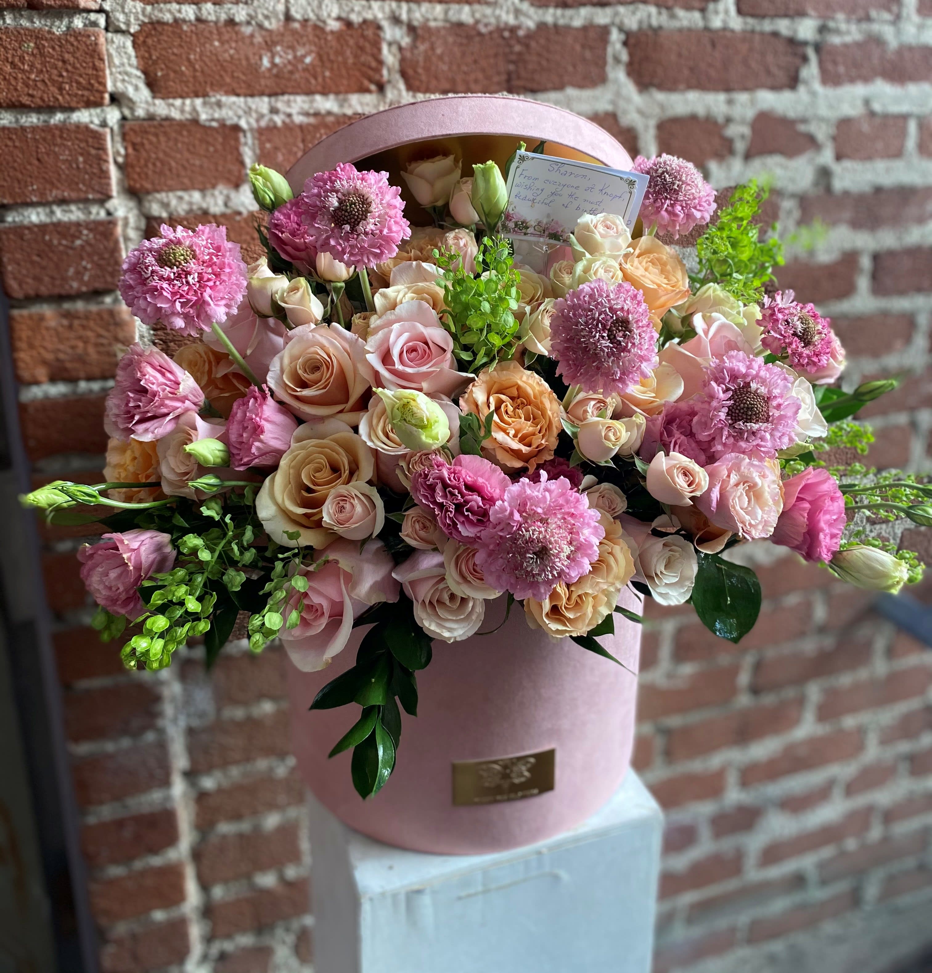 Pink and peach rose bouquet in a round pink box with green accents