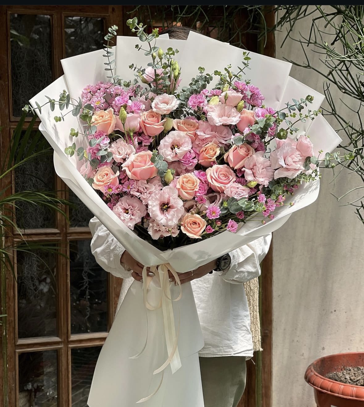 Large bouquet of pink roses and lisianthus with eucalyptus in white wrap