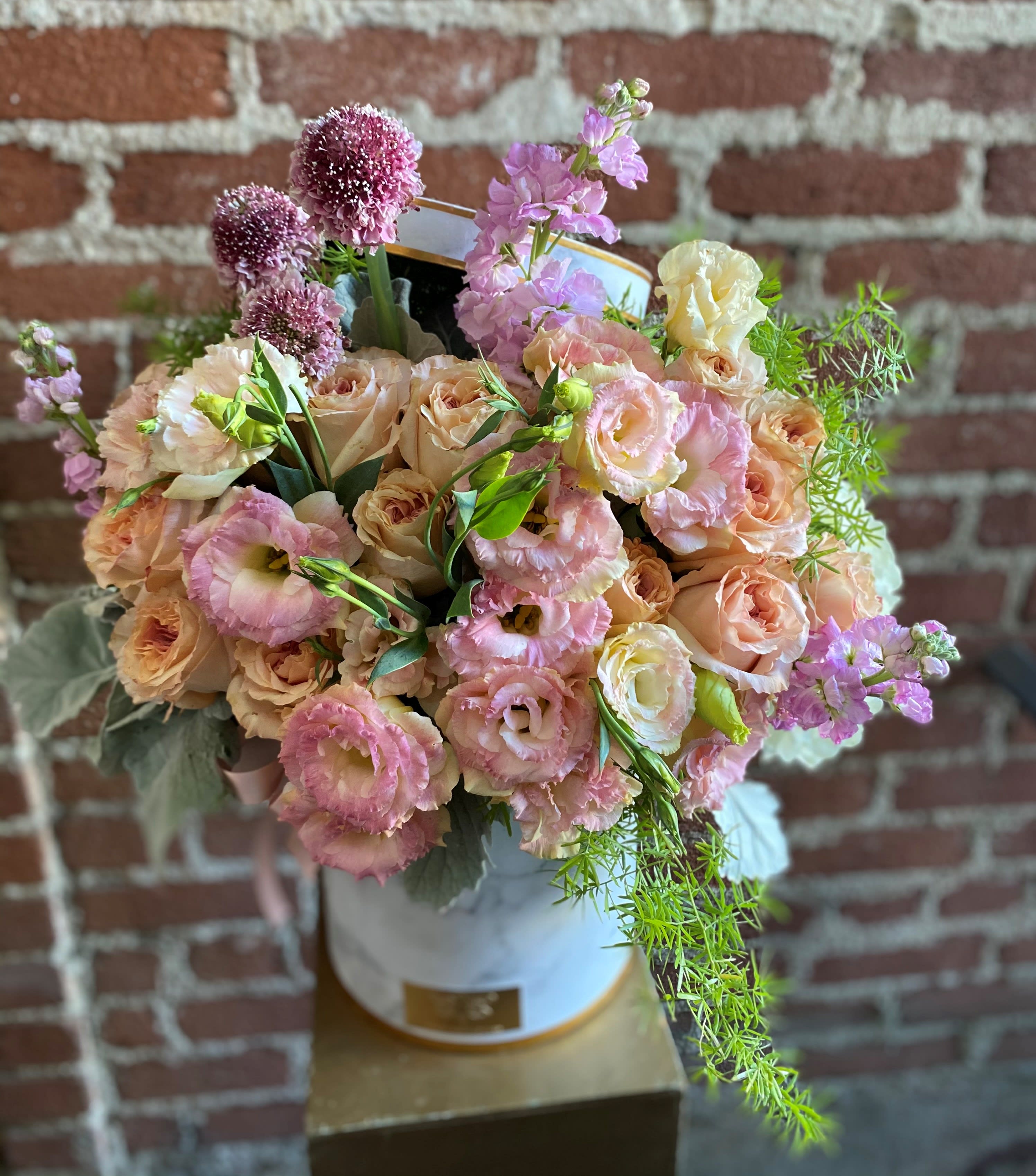 Pastel bouquet of roses and lisianthus in a white hatbox