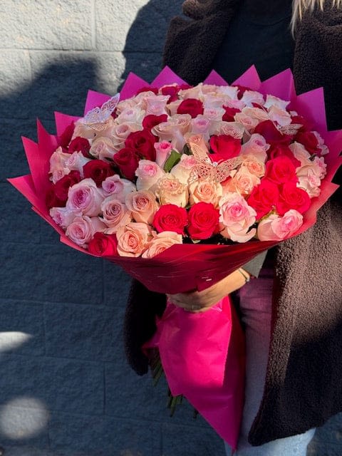 Large bouquet of pink and red roses wrapped in bright pink paper