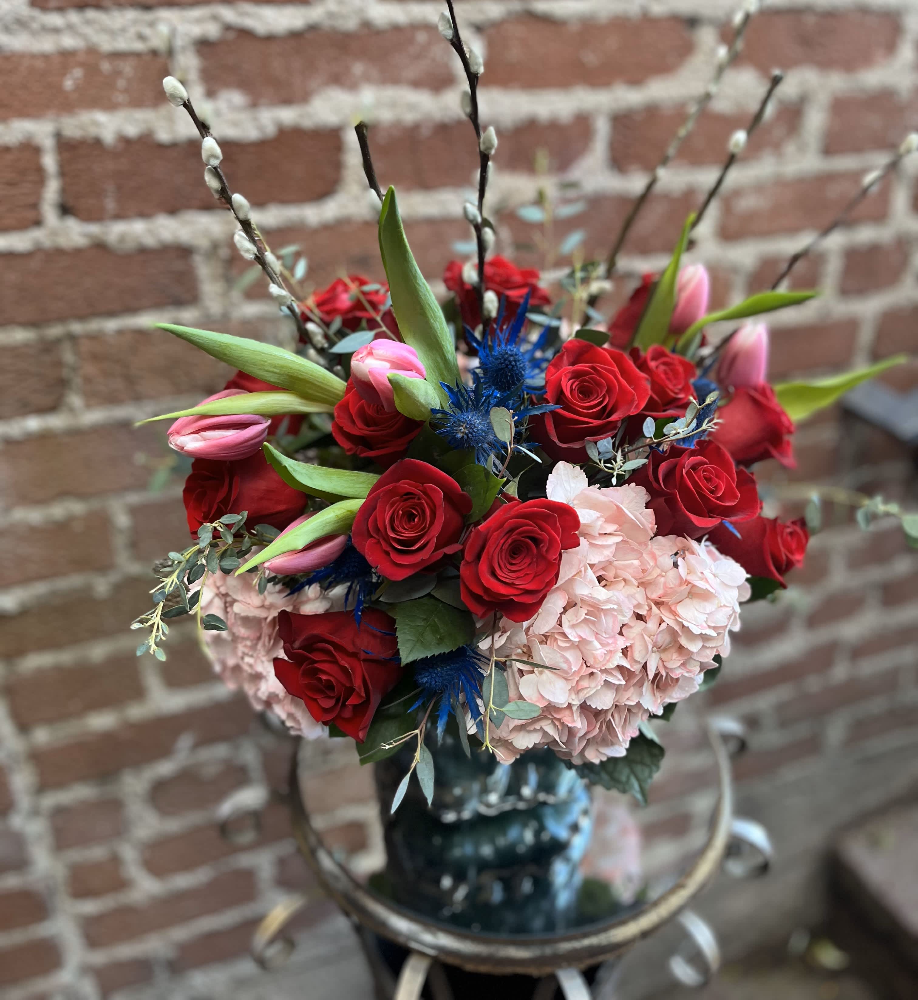 Bouquet of red roses, pink tulips, and pale hydrangea in a vase