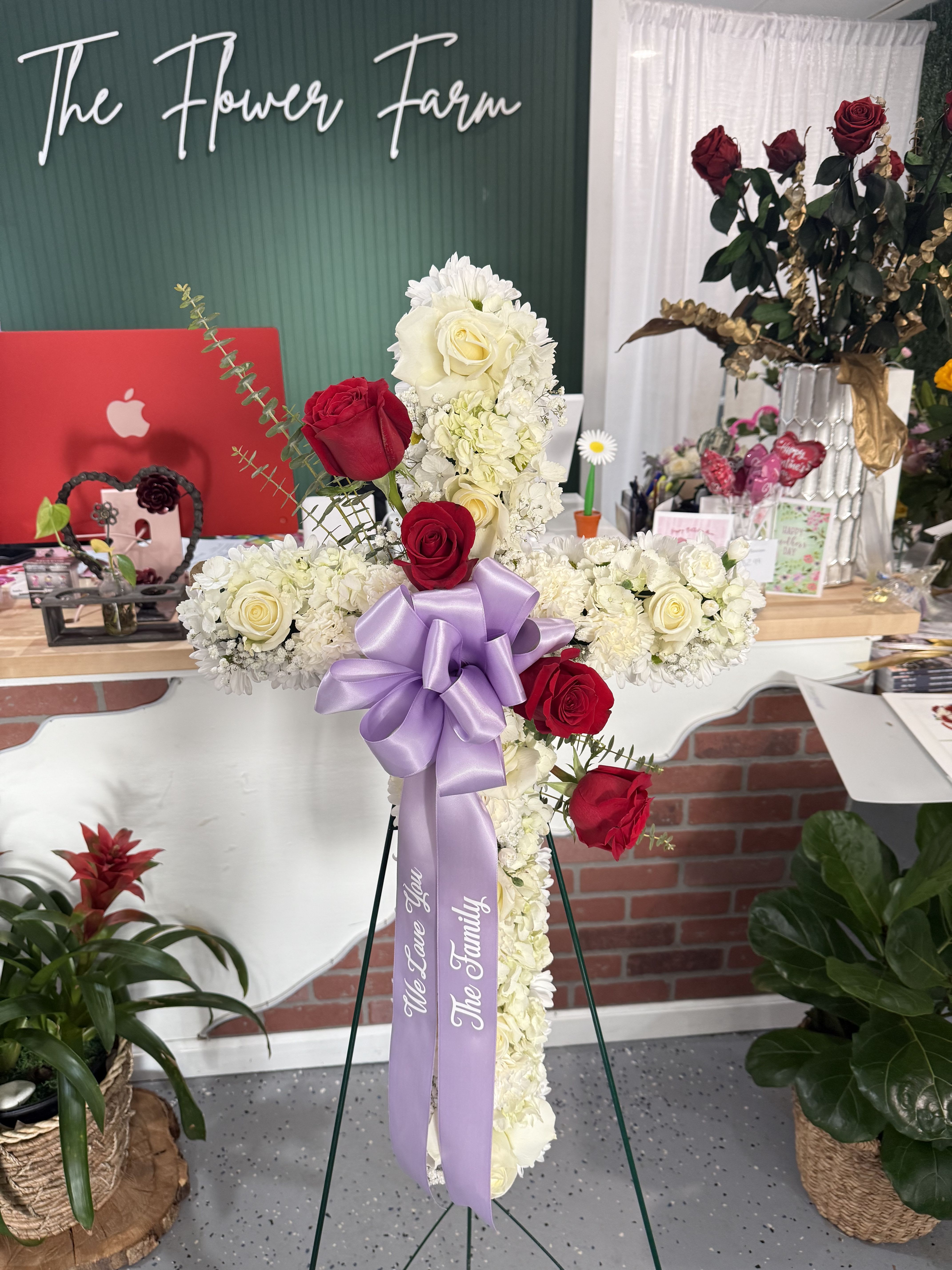 Cross-shaped floral tribute with red and white roses and a lavender ribbon