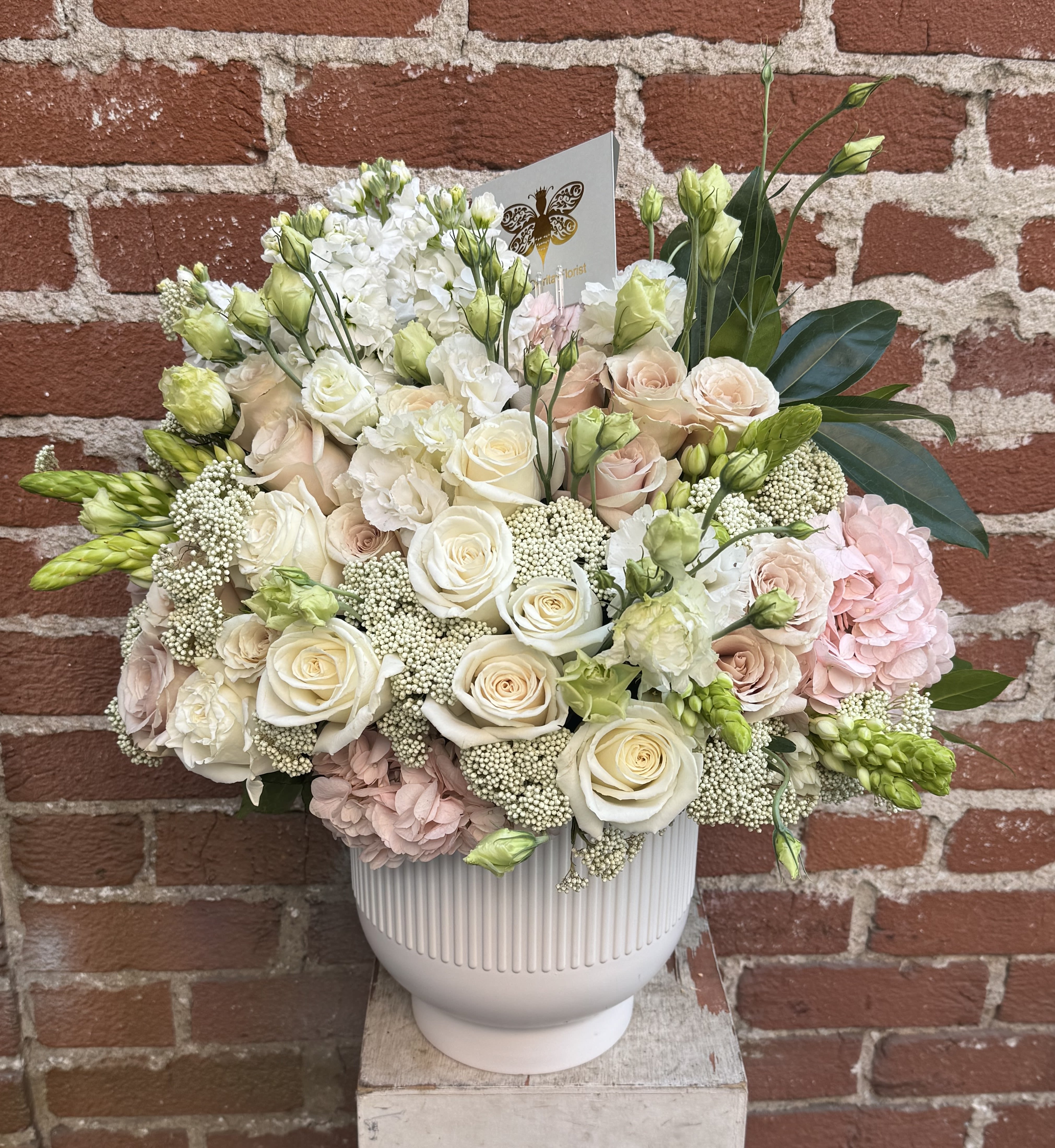 Cream and blush floral arrangement in a white ribbed vase