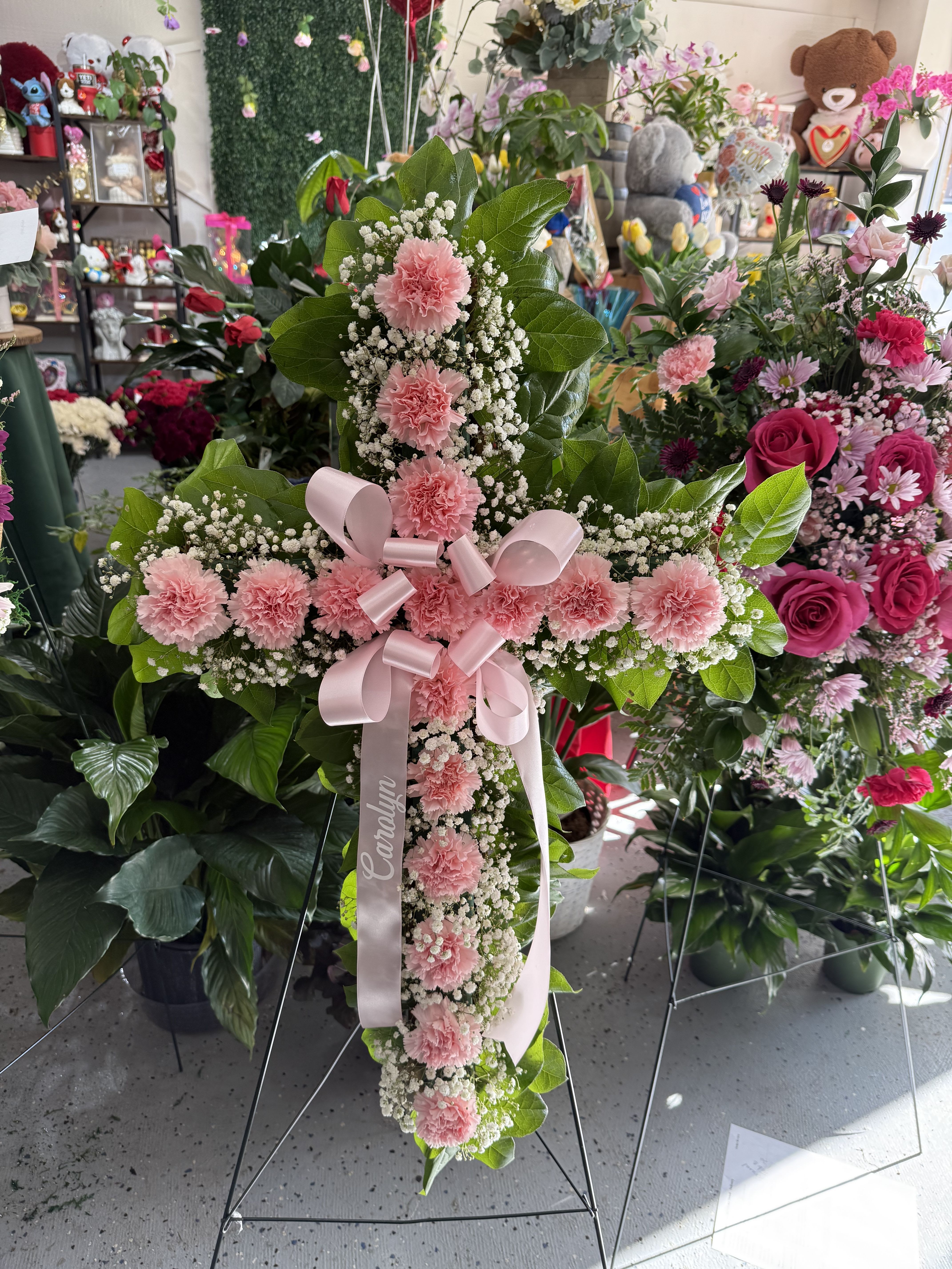 Pink carnation cross on a stand with a ribbon bow