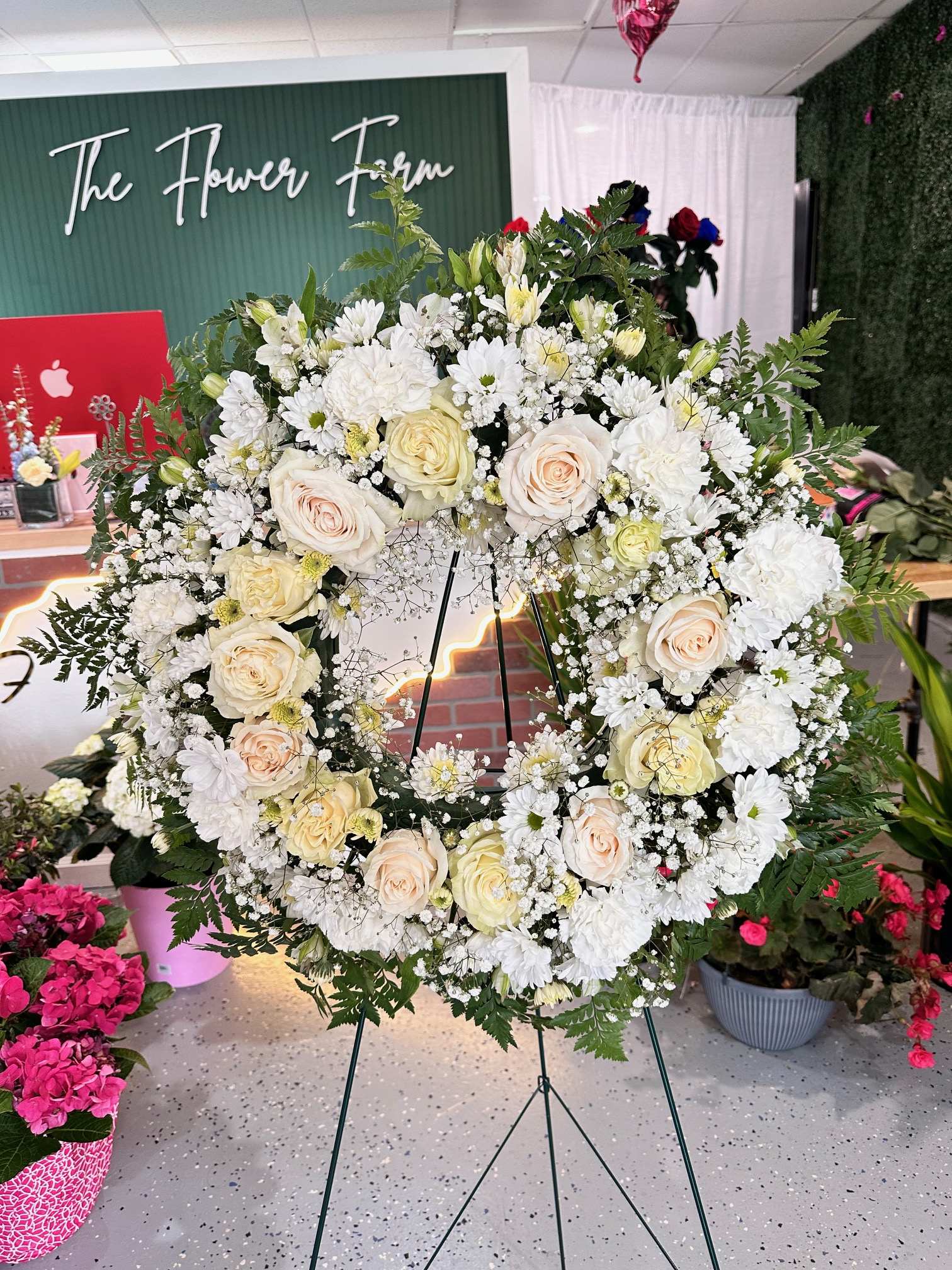 Large white floral wreath on a stand with cream roses and daisies