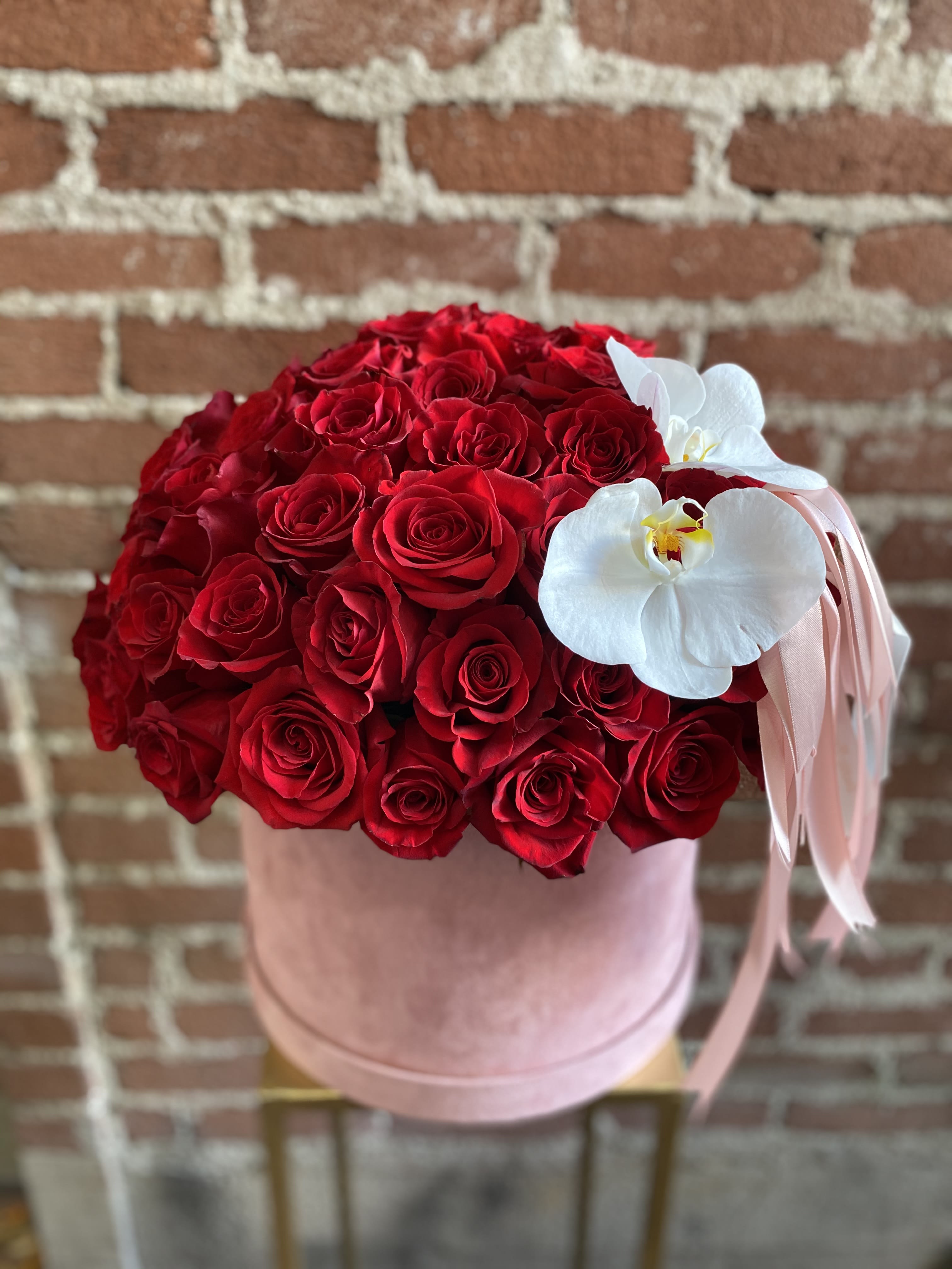 Red rose bouquet in a pink hat box with white orchids and ribbon
