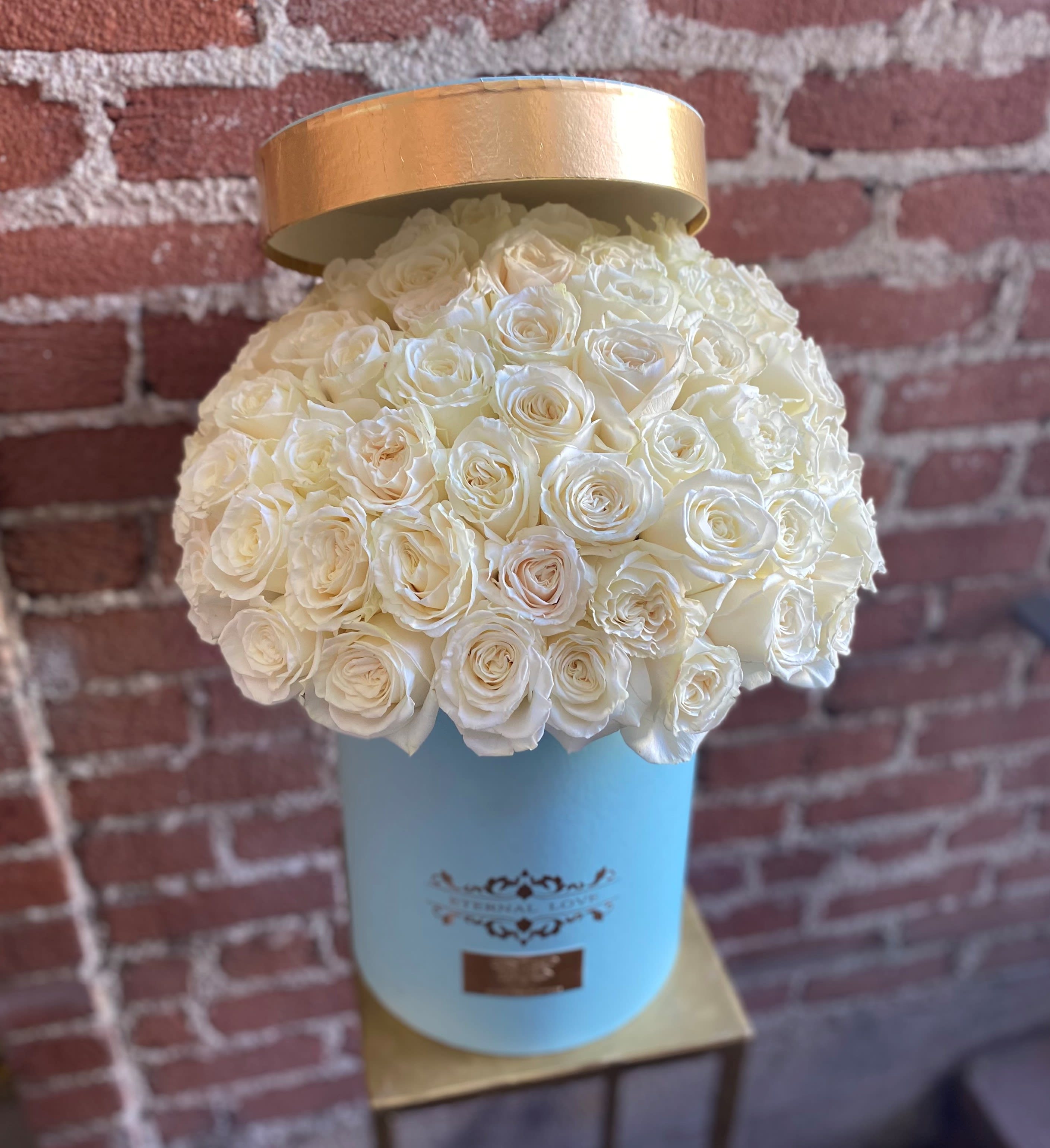 White rose bouquet in a light blue hat box with a gold lid