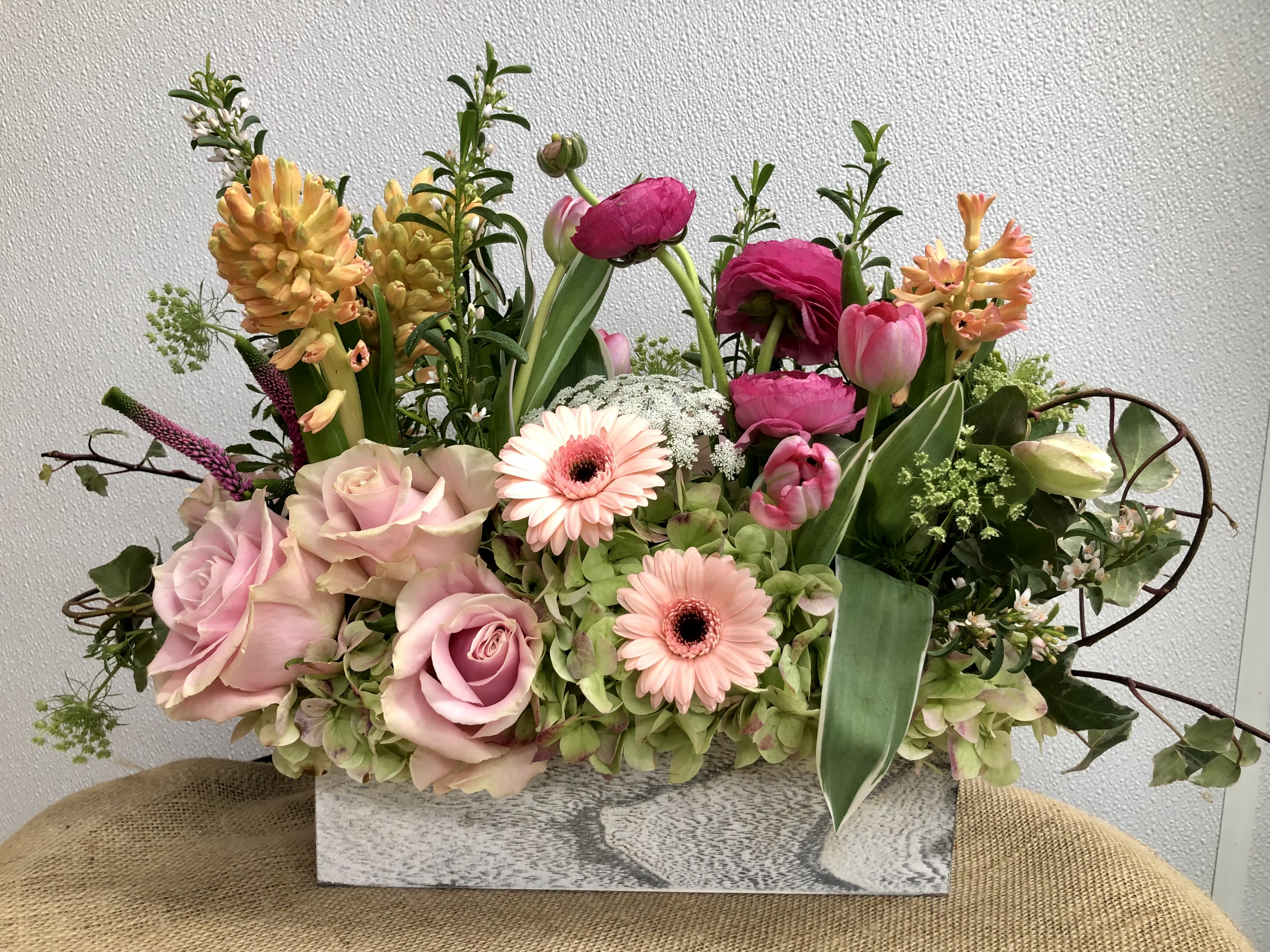 Mixed bouquet with pink roses, gerbera daisies, tulips, and hyacinths in a rectangular vase