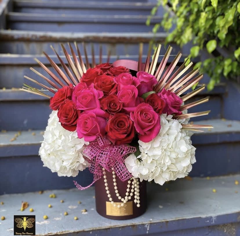 Bouquet of red and pink roses with white hydrangeas in a dark vase