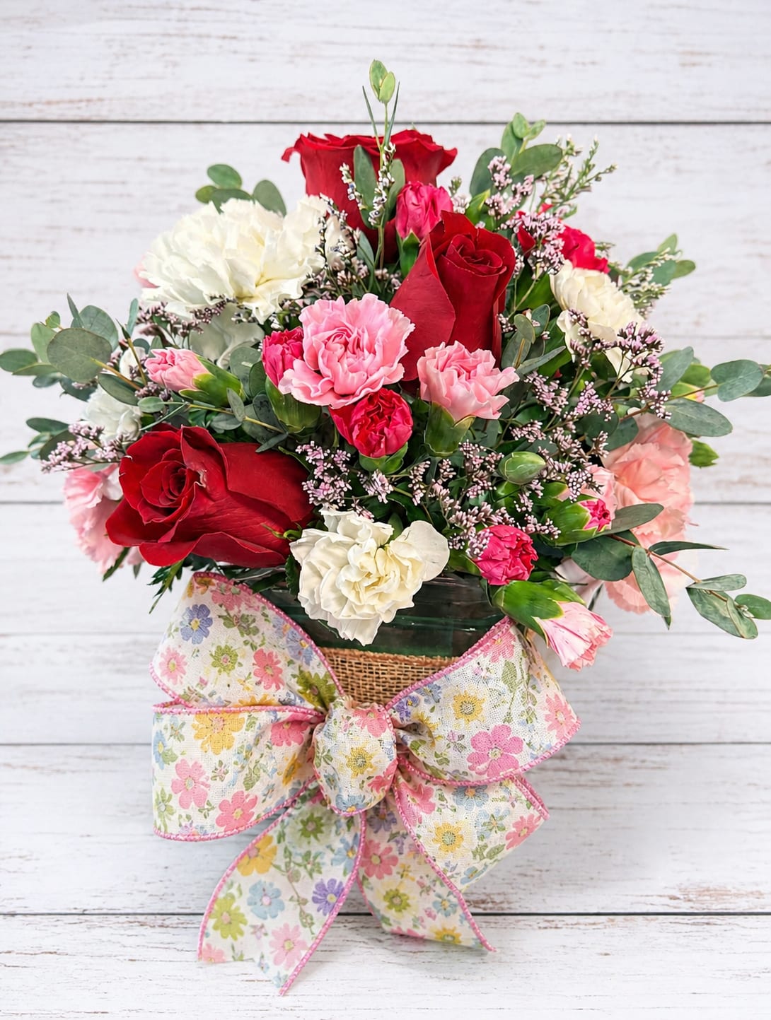 Spring Cube - A cheerful cube arrangement bursting with sunshine and charm. Bright roses are paired with soft carnations and playful daisies, all tucked among fresh greenery and delicate filler for a light, airy feel. Designed in a classic cube vase, it’s the perfect pop of color for a desk, kitchen table, or thoughtful gift.