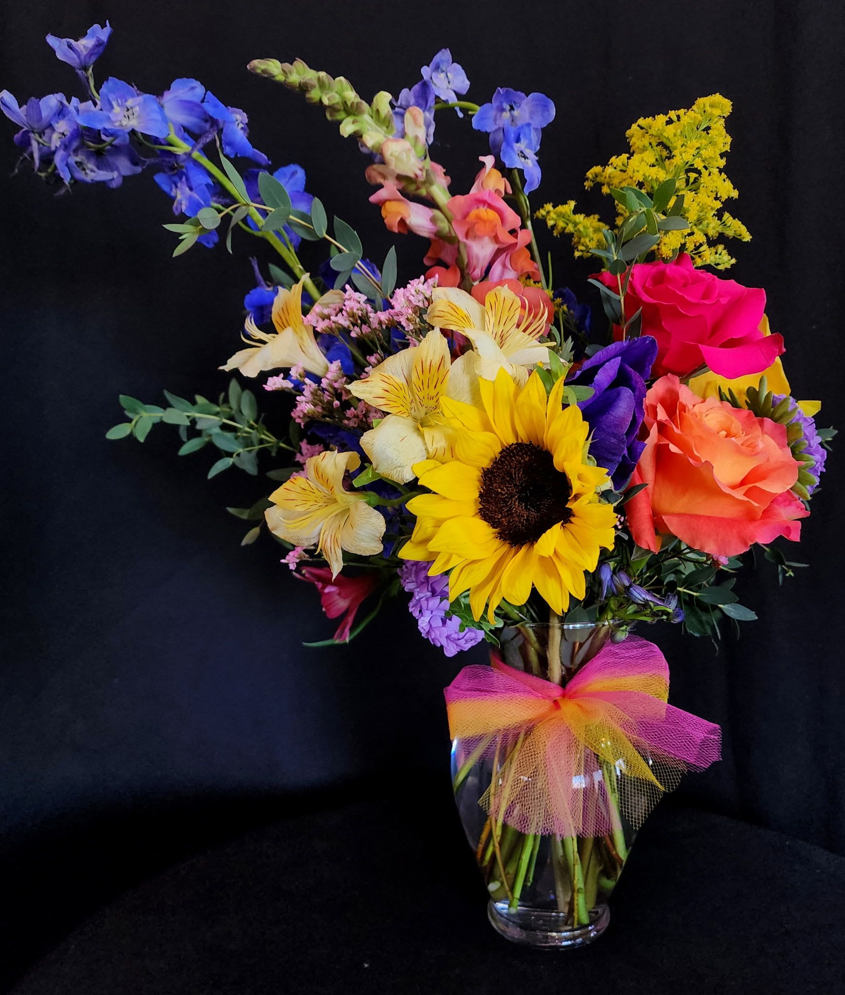 Mini Tucson Sunrise - Miniature version of our Tucson Sunrise. Wake up with this beautiful bouquet or send it to that special person that you care about and love. This arrangement represents our fabulous desert sunrise over the Rincon Mountains with a shade of colors including blue, yellow, orange, and red.   Dimensions are as follows:  18" Height x 13" Length x 9" Width in an 7 1/2" glass vase. 