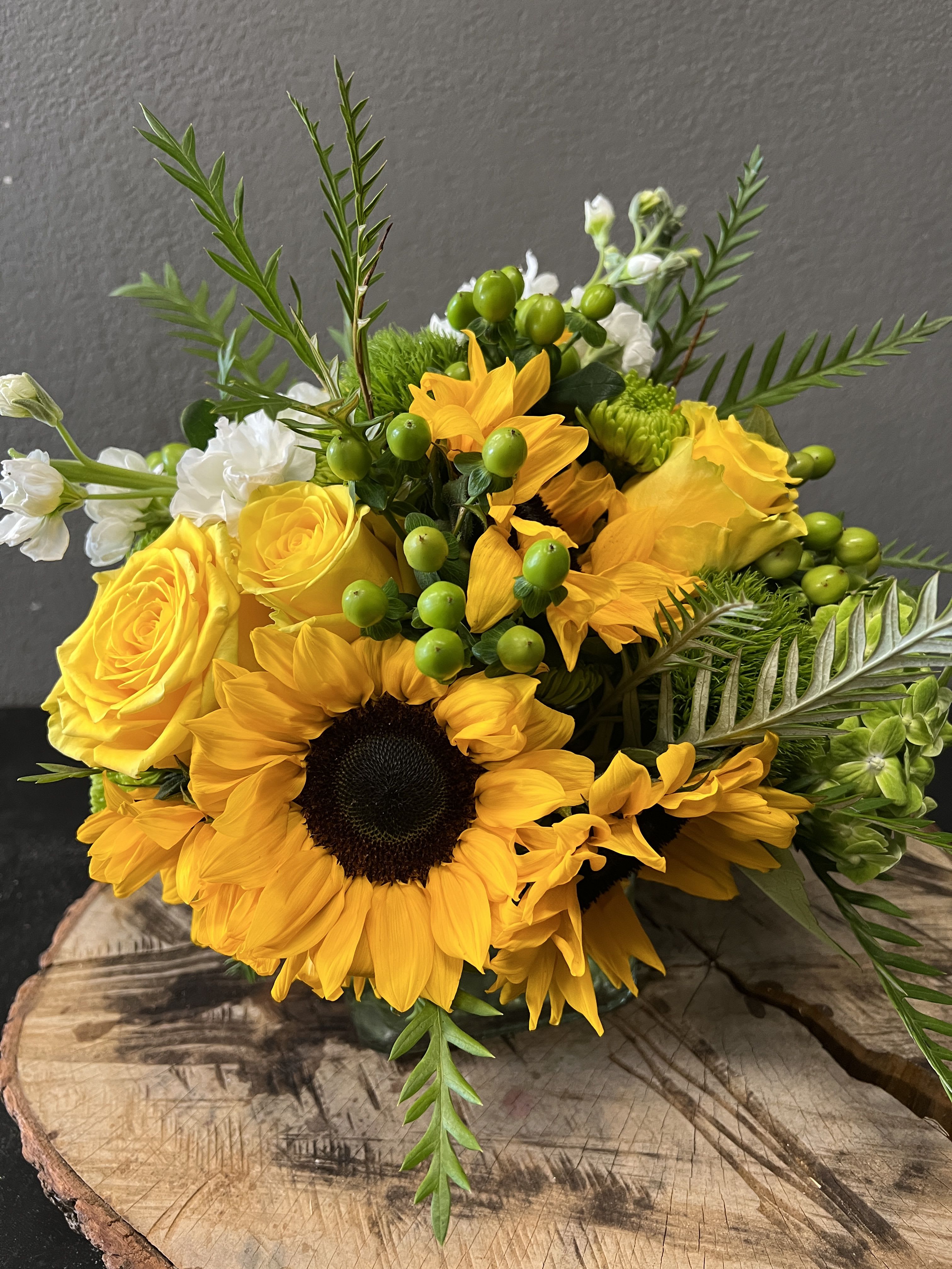 Yellow sunflowers and roses with green berries in a bouquet