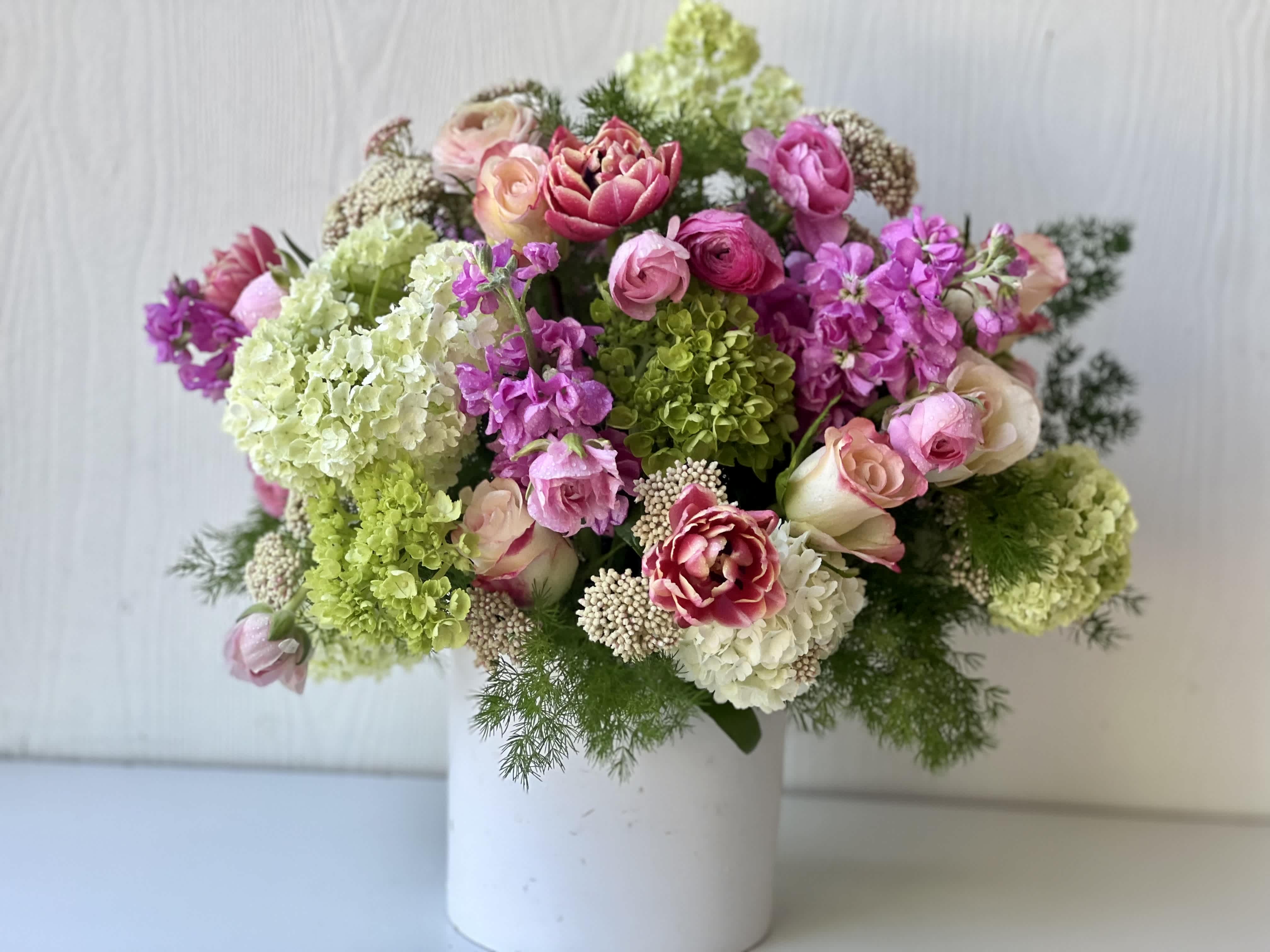 Mixed pink and green floral arrangement in a white vase