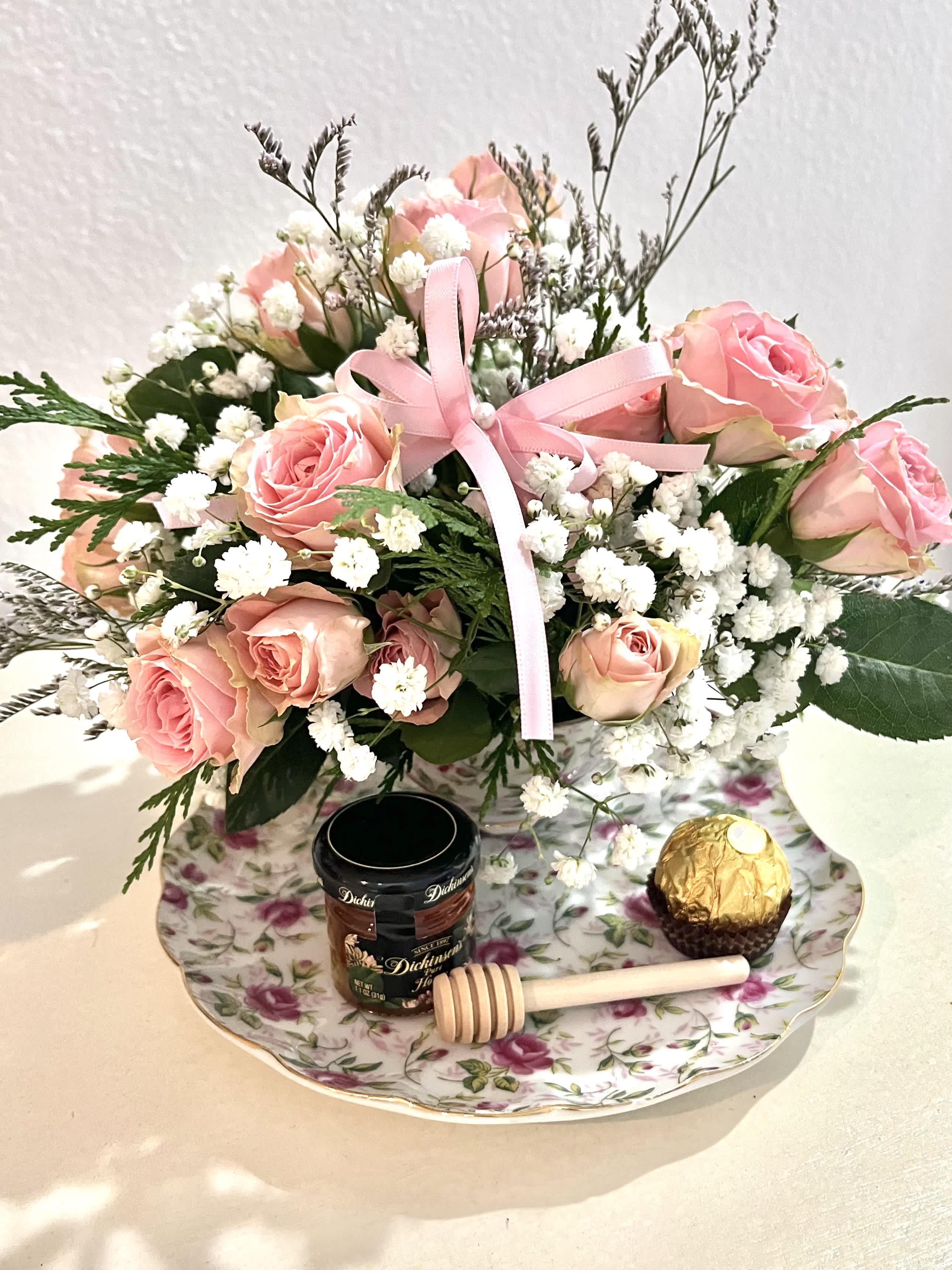 Pink rose bouquet with baby's breath, ribbon, and chocolates on a floral tray