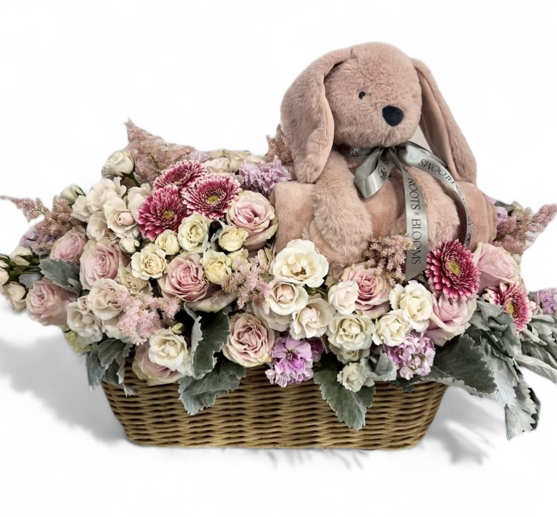 Basket of pastel flowers with a plush bunny