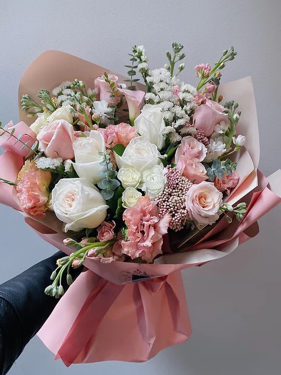 Hand-tied bouquet of pink and white roses with pink wrapping