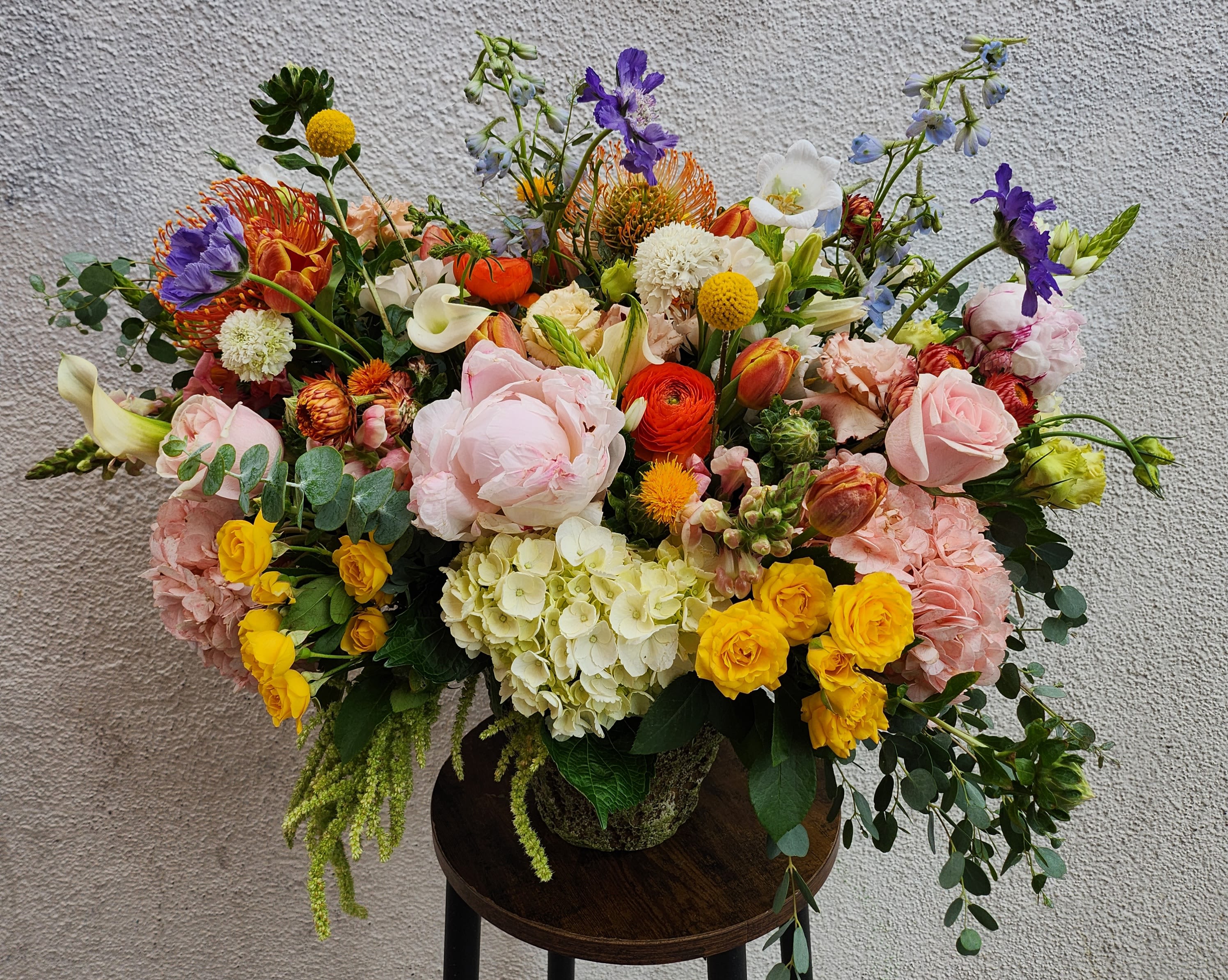 Large mixed bouquet in a vase with pink, yellow, orange, purple, and white flowers