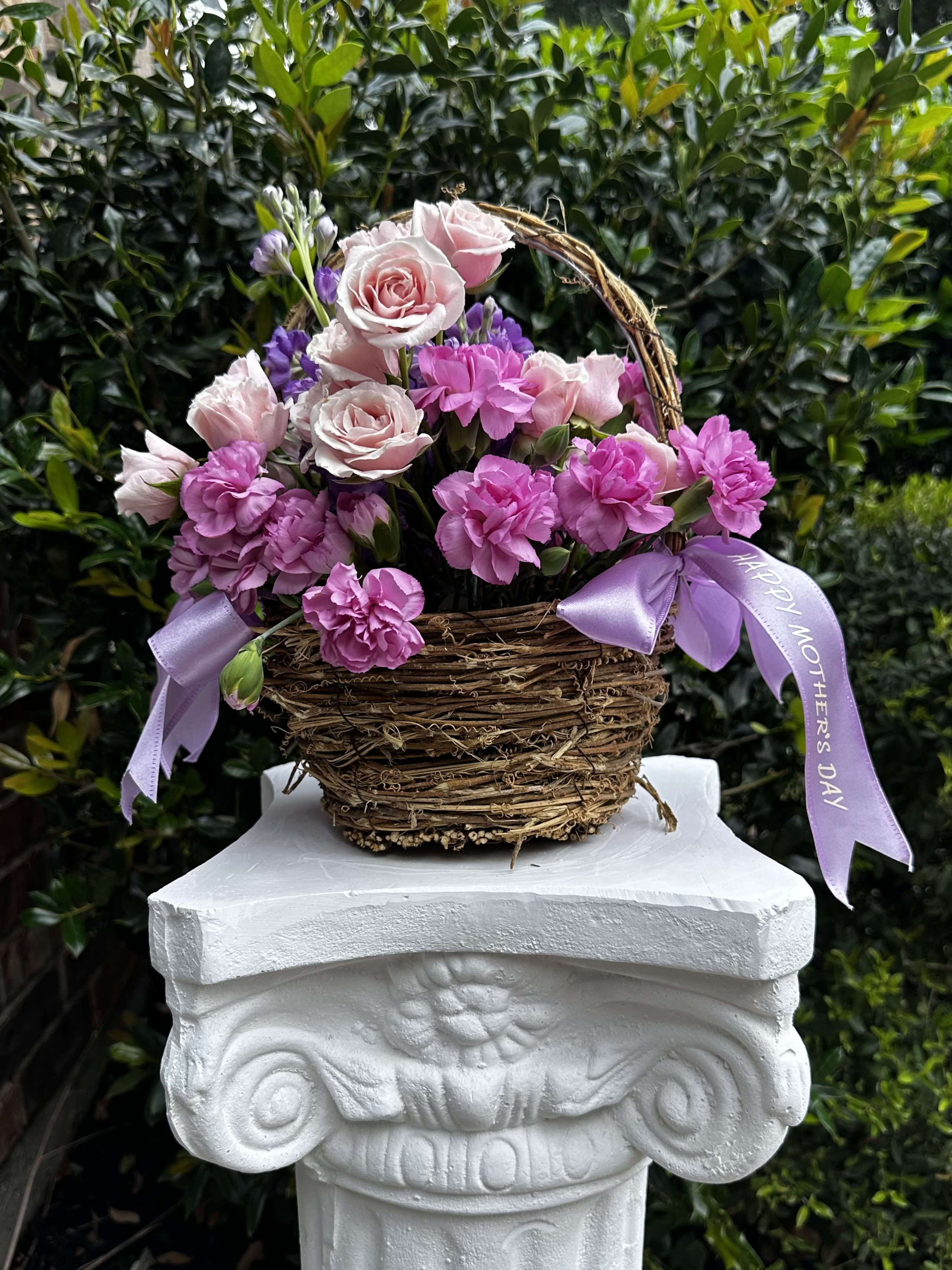Pink roses and carnations in a wicker basket with lavender ribbons