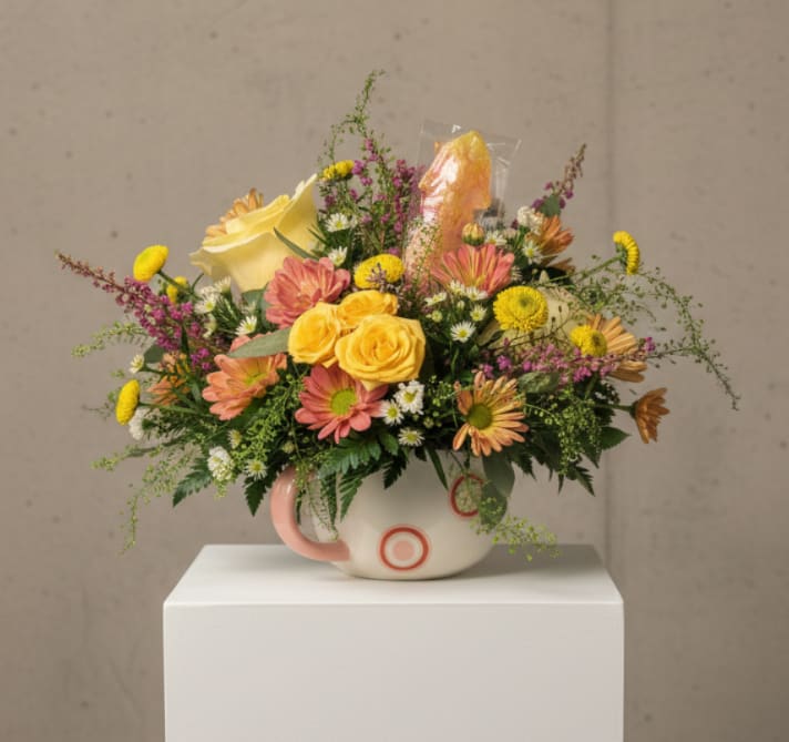 Mixed bouquet in a white mug-style vase with yellow and pink flowers