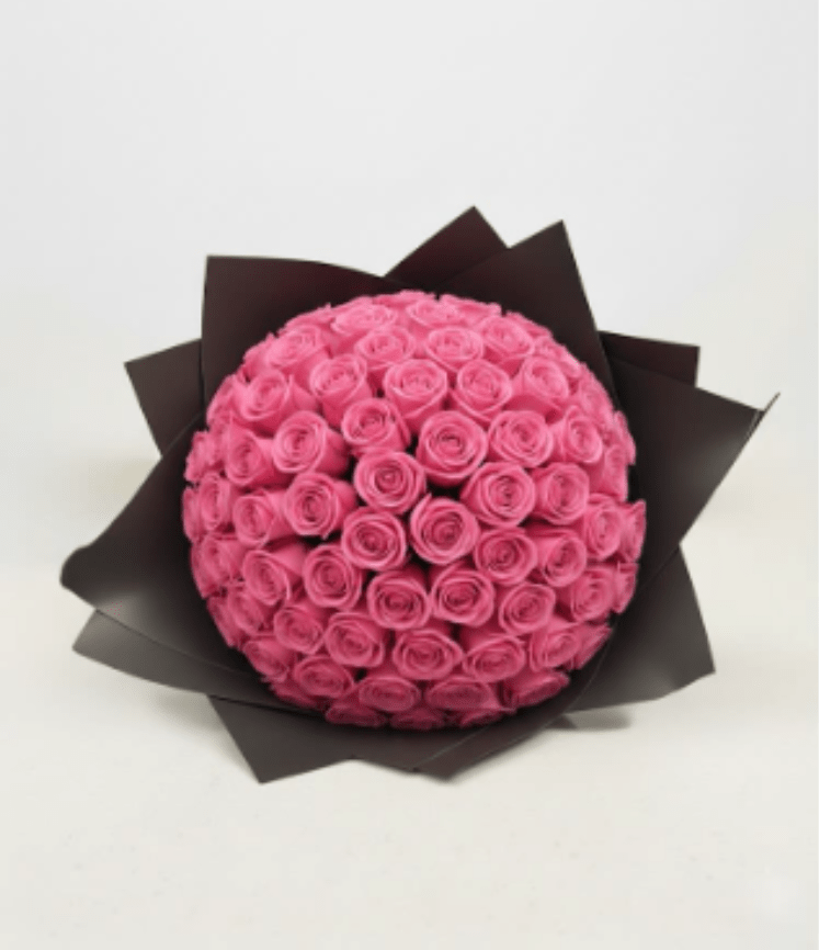 Round bouquet of pink roses wrapped in dark paper