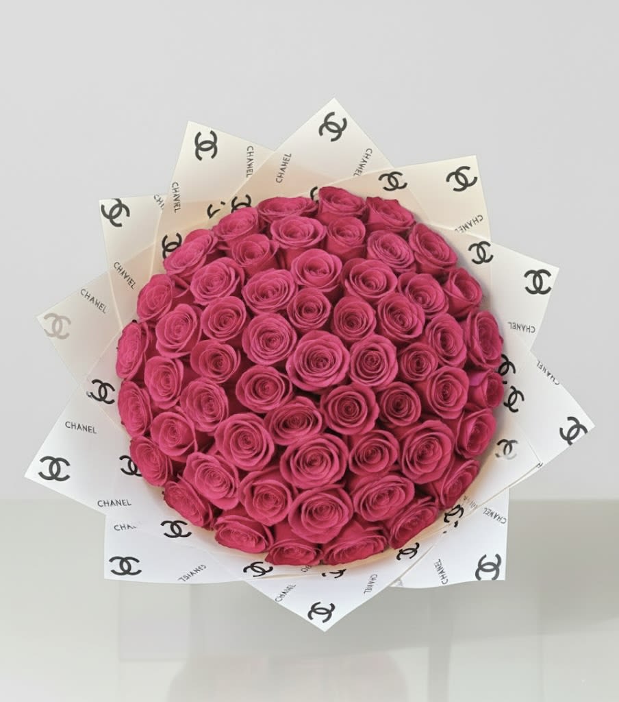Bouquet of bright pink roses wrapped in Chanel-logo paper