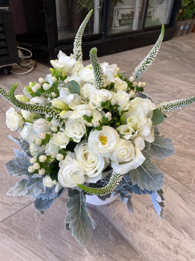 White floral bouquet with tall spiky accents in a white container