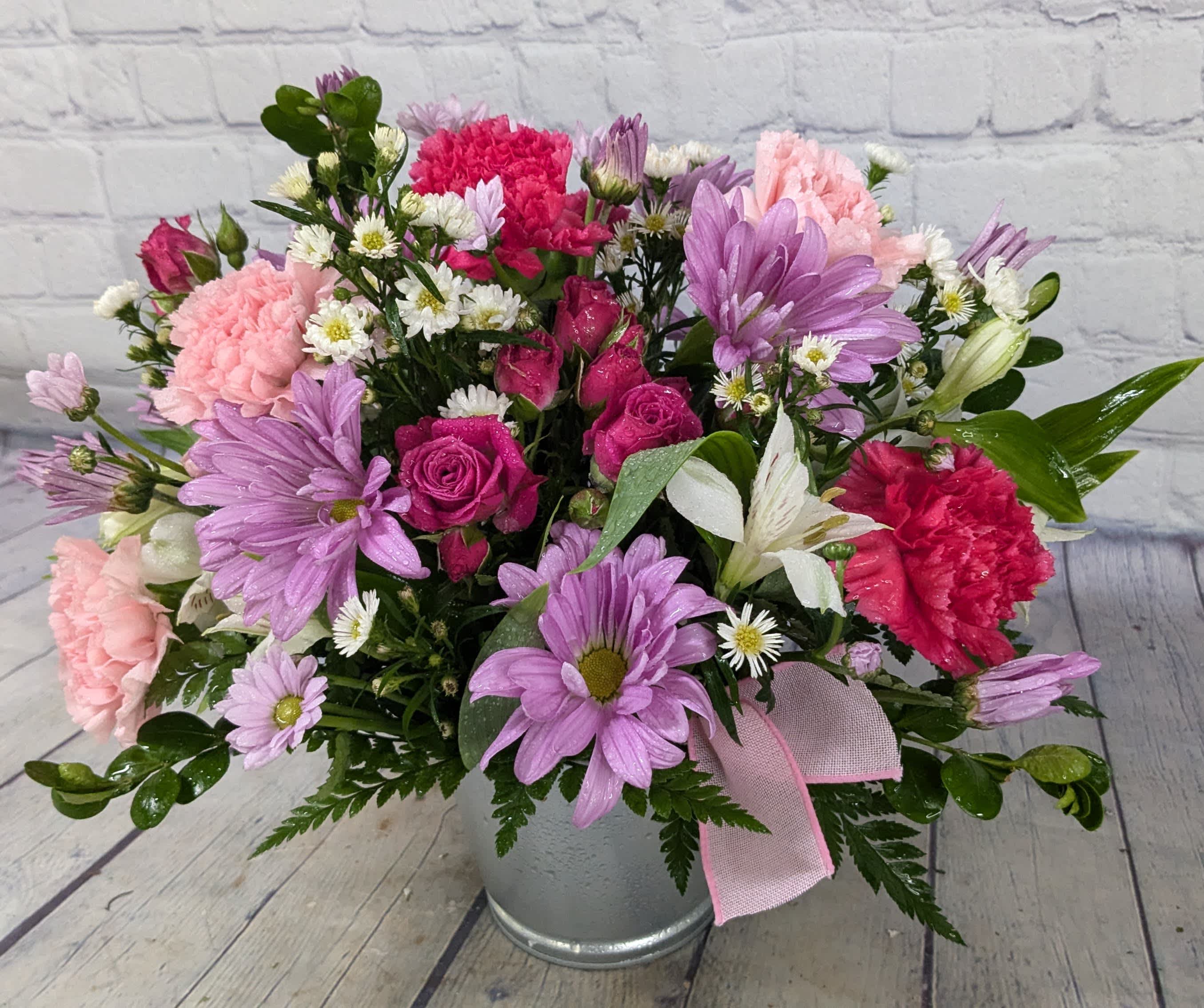 Pink and purple mixed flower arrangement in a metal bucket with a ribbon