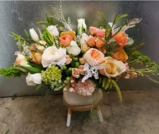 Mixed bouquet of peach, white, and coral flowers in a vase