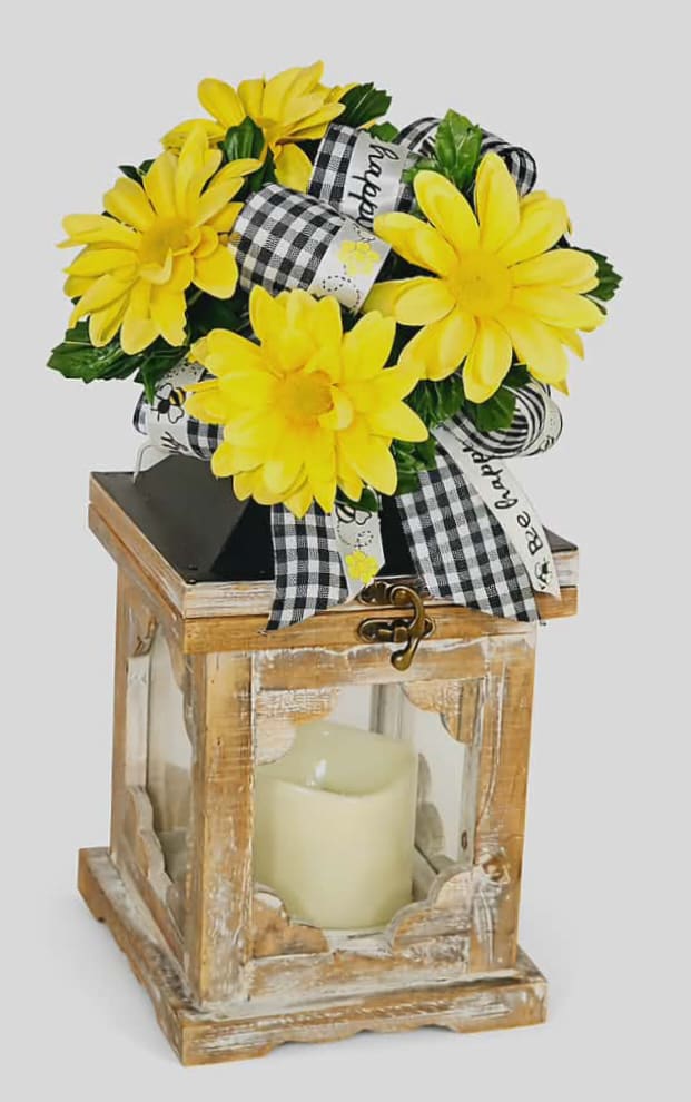 Yellow daisy bouquet on a rustic lantern with a candle inside