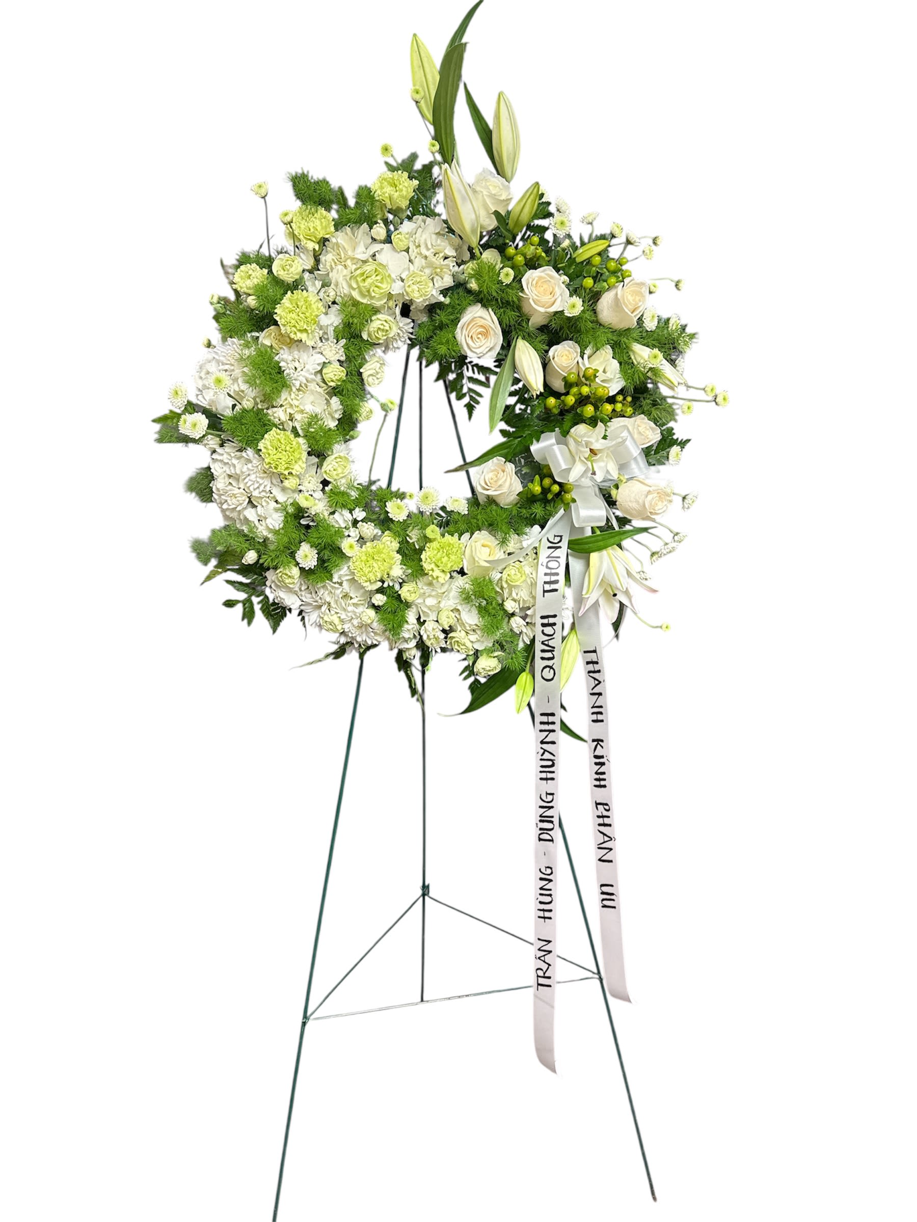 White and green funeral wreath on a stand with ribbon