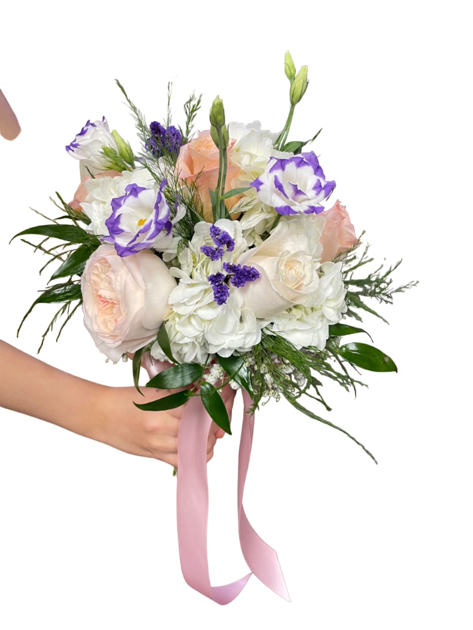 Handheld bouquet of pale roses, white blooms, and purple-edged flowers with a pink ribbon