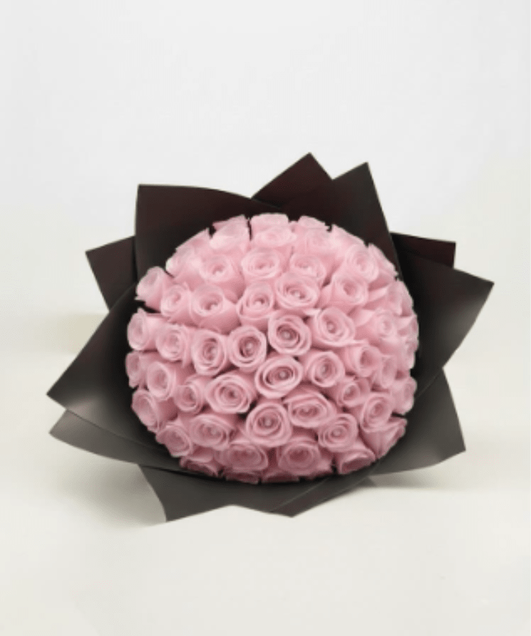 Bouquet of pale pink roses wrapped in dark paper