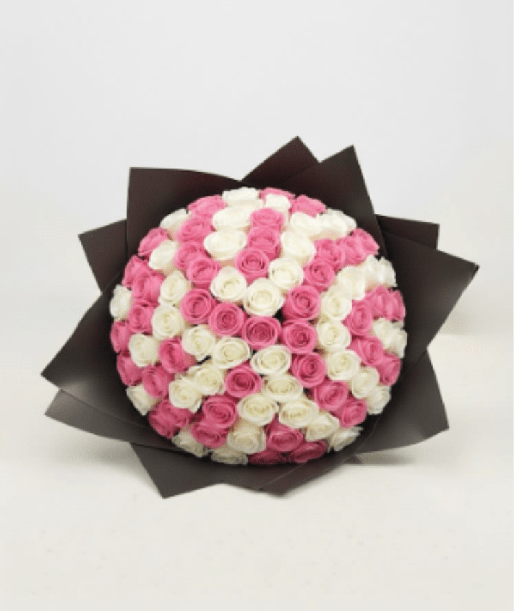 Bouquet of pink and white roses wrapped in dark paper