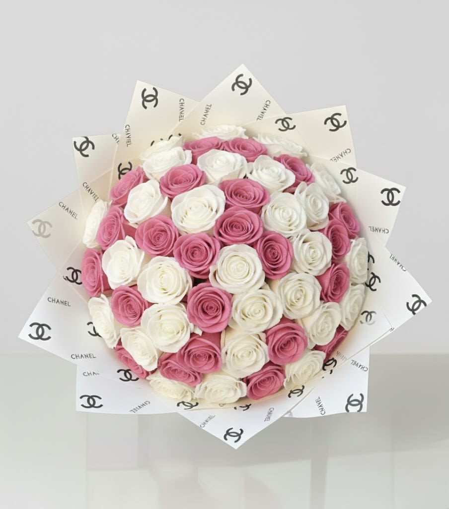 Round bouquet of pink and white roses wrapped in Chanel-logo paper