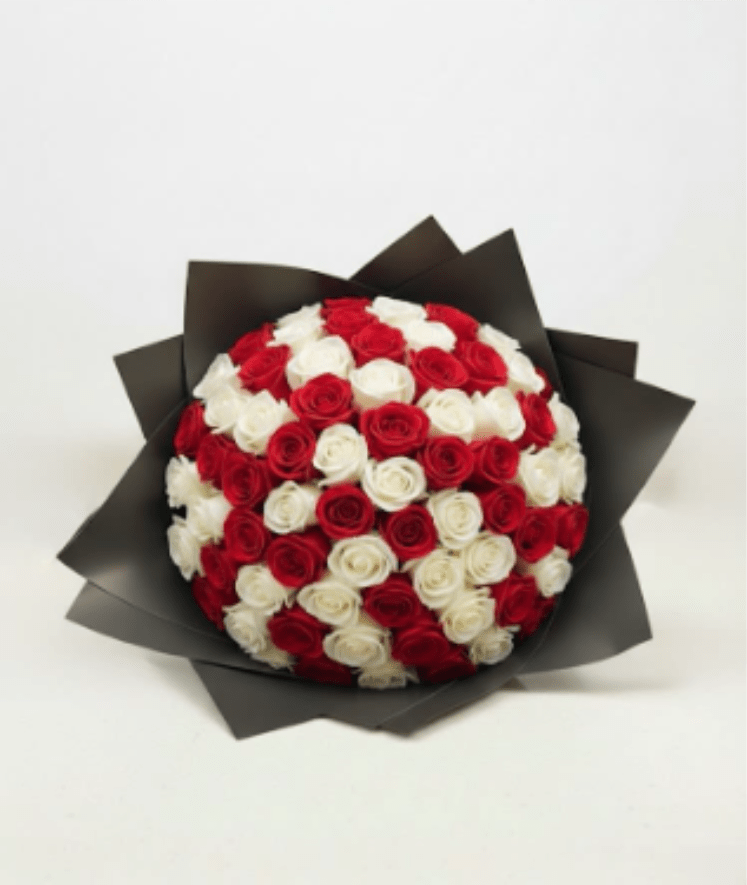 Round bouquet of red and white roses wrapped in dark paper