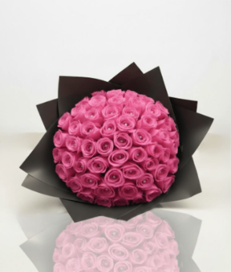 Round bouquet of bright pink roses wrapped in black paper