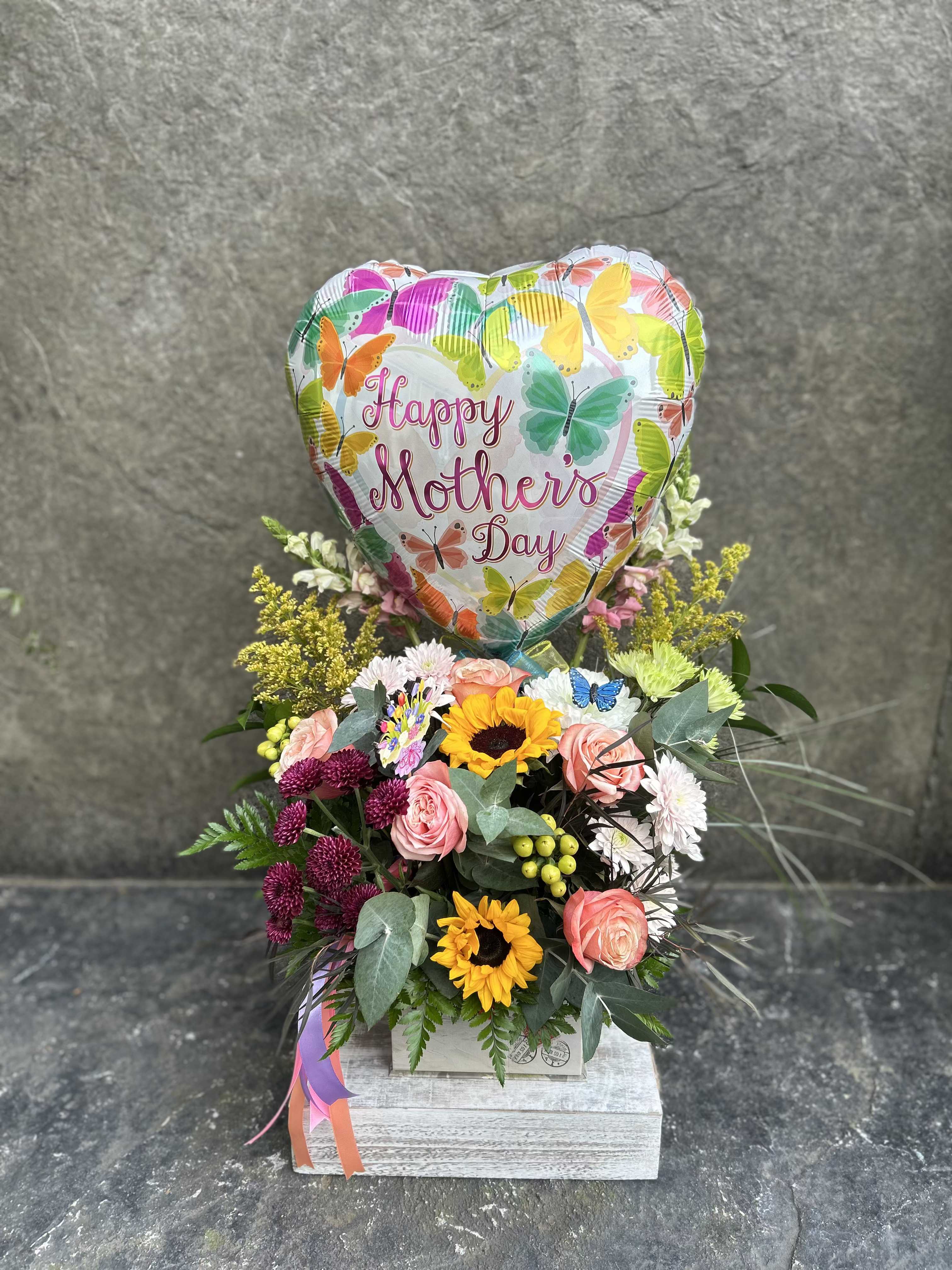 Happy Mothers Day - Flower box with sunflowers, snapdragons, roses, chrysanthemums, berries, asters, with eucalyptus and other pretty greenery. Decorated with a Mday balloon and ribbons. *Balloon will be assorted and not same as pictured but will be mothers day themed and match flowers.