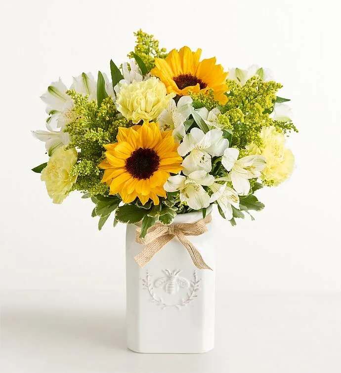Honey Bee Buzz for Summer - Get them buzzing for summer! This unique bouquet is gathered with a mix of blooms in bright, happy yellow and white. Designed in a Sweet As Can Bee artisanal vase, featuring an adorable honeybee and a raffia bow, it’s a gift that adds radiant beauty to any decor.