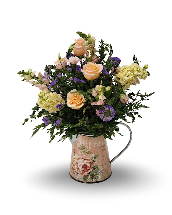 Peach roses and purple flowers arranged in a floral metal pitcher