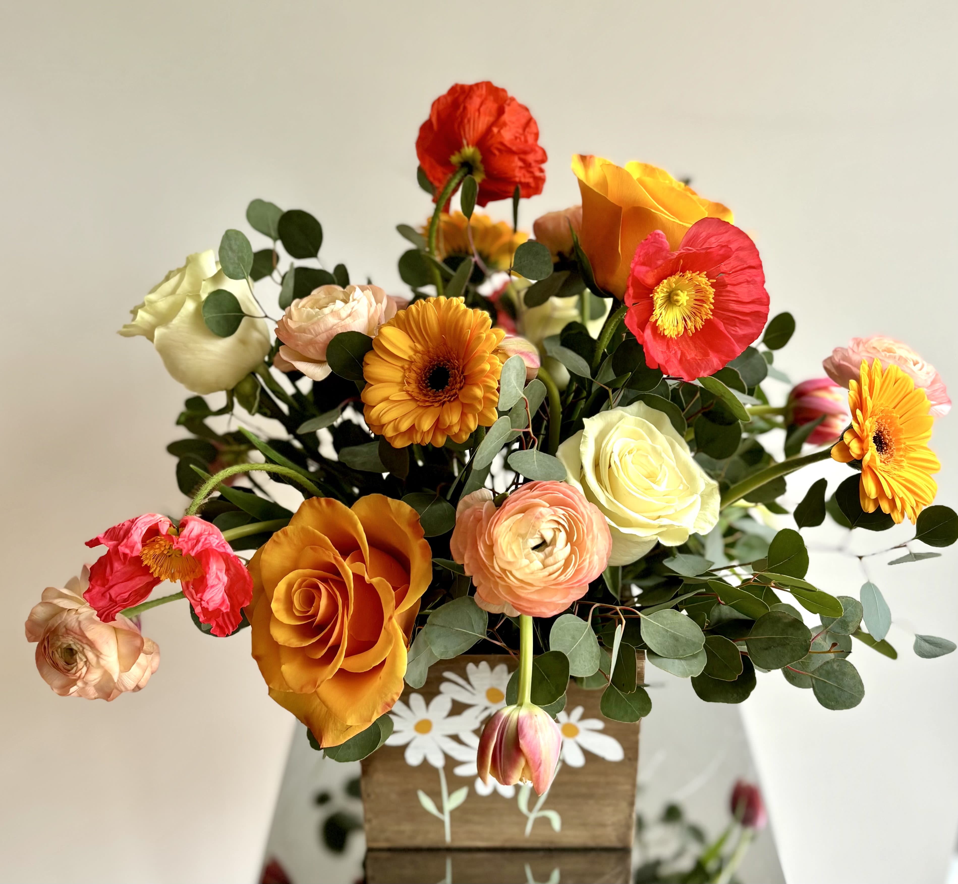 Mixed bouquet of orange, pink, red, and white flowers in a wooden box