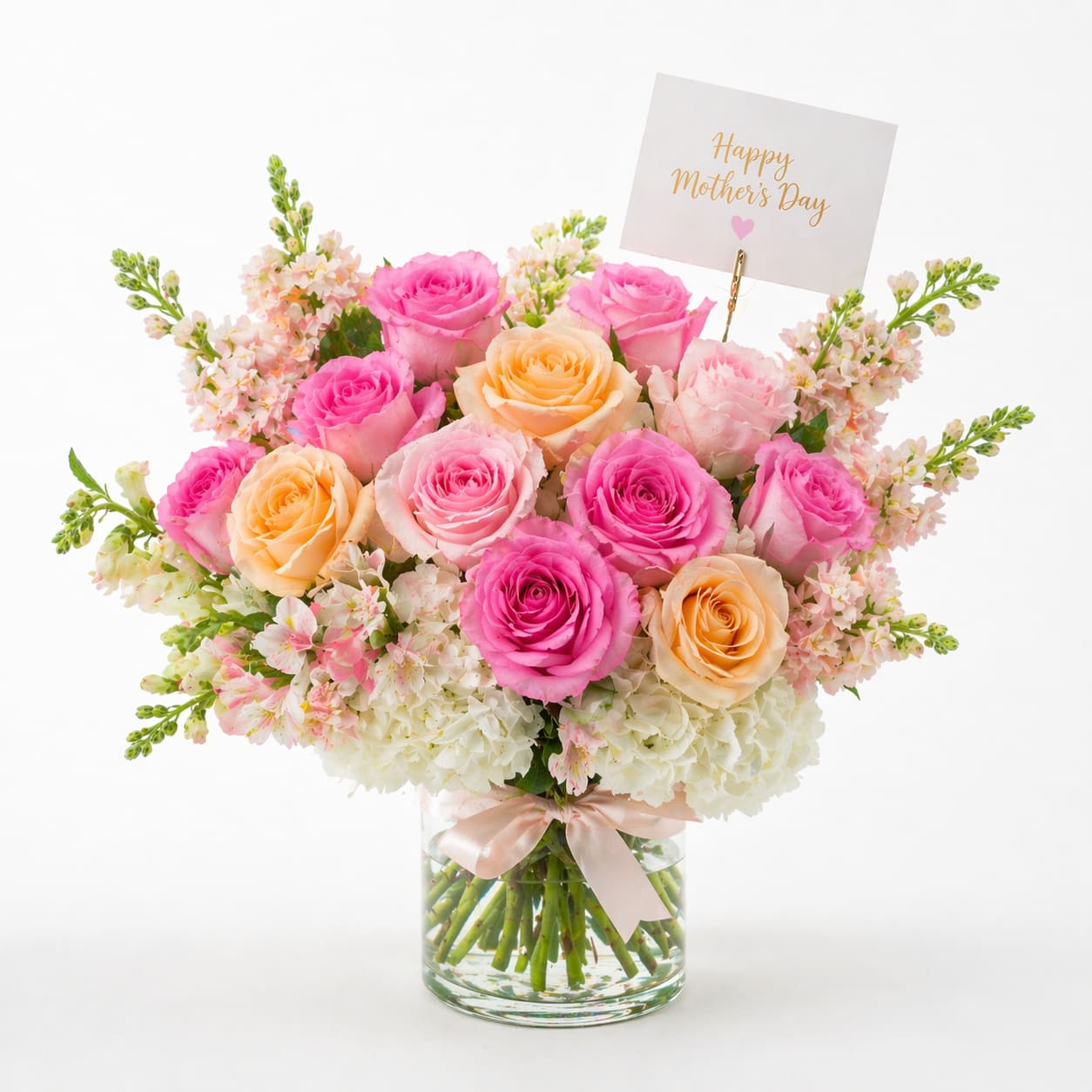 Mother's Day flower - A joyful cluster of pink and peach roses with pale white hydrangeas-this Mother's Day bouquet feels like a warm spring embrace. Perfect as a Mother's Day arrangement or a celebratory gift for a mom, grandmother, or special woman in your life, the rounded, full shape reads romantic and bright so she'll feel genuinely celebrated the moment she sees it.  Tightly arranged roses and lush hydrangea heads are softened with small airy filler blooms for texture and movement. The mix of pink, peach and white creates a fresh, feminine palette, presented in a clear glass vase tied with a soft pink ribbon. A small greeting card clipped into the design offers a place for your personal message.  This is the kind of bouquet that arrives ready to display-ideal for breakfast surprises, brunch tables, or a bedside delight. Standard vase dimensions and care are simple: keep flowers in fresh water, trim stems every few days, and refresh water to extend bloom life. Order with a personalized card message to make the moment unmistakably hers.