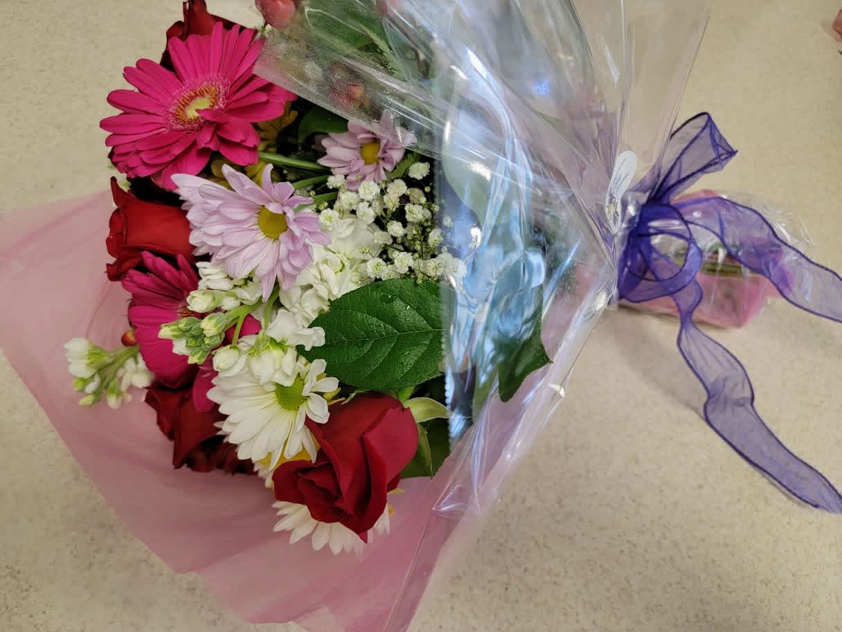 Bouquet of red roses, pink gerbera daisies, and white daisies wrapped in pink and clear plastic